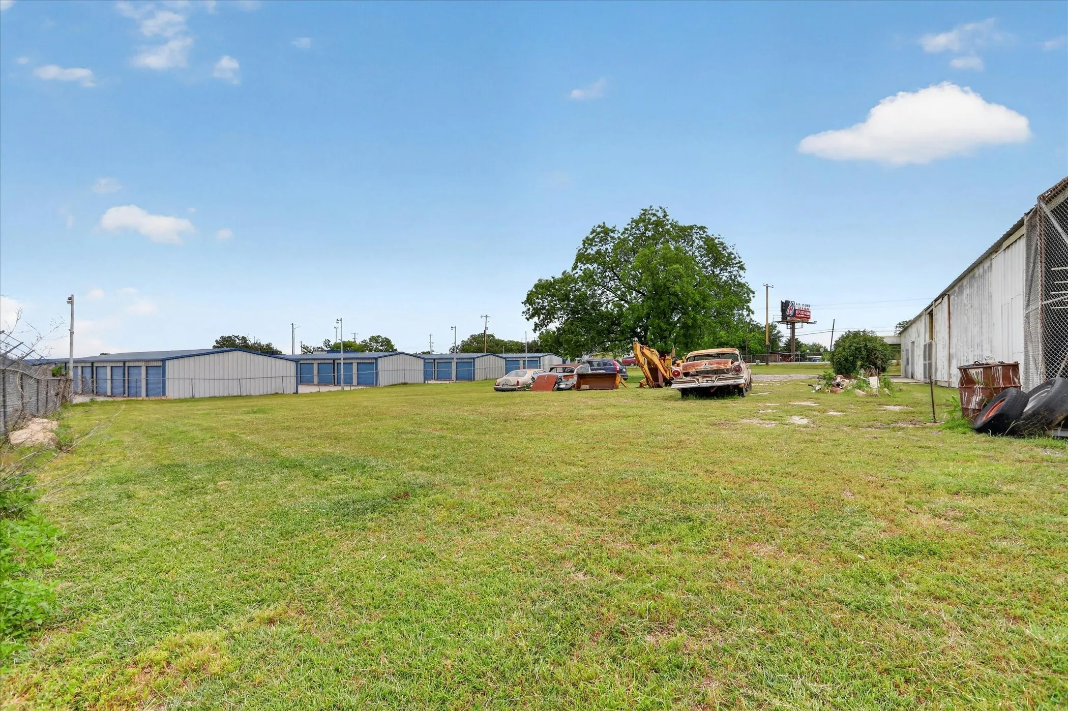 Expansive grass lot bordered by chain link fencing and mature trees
