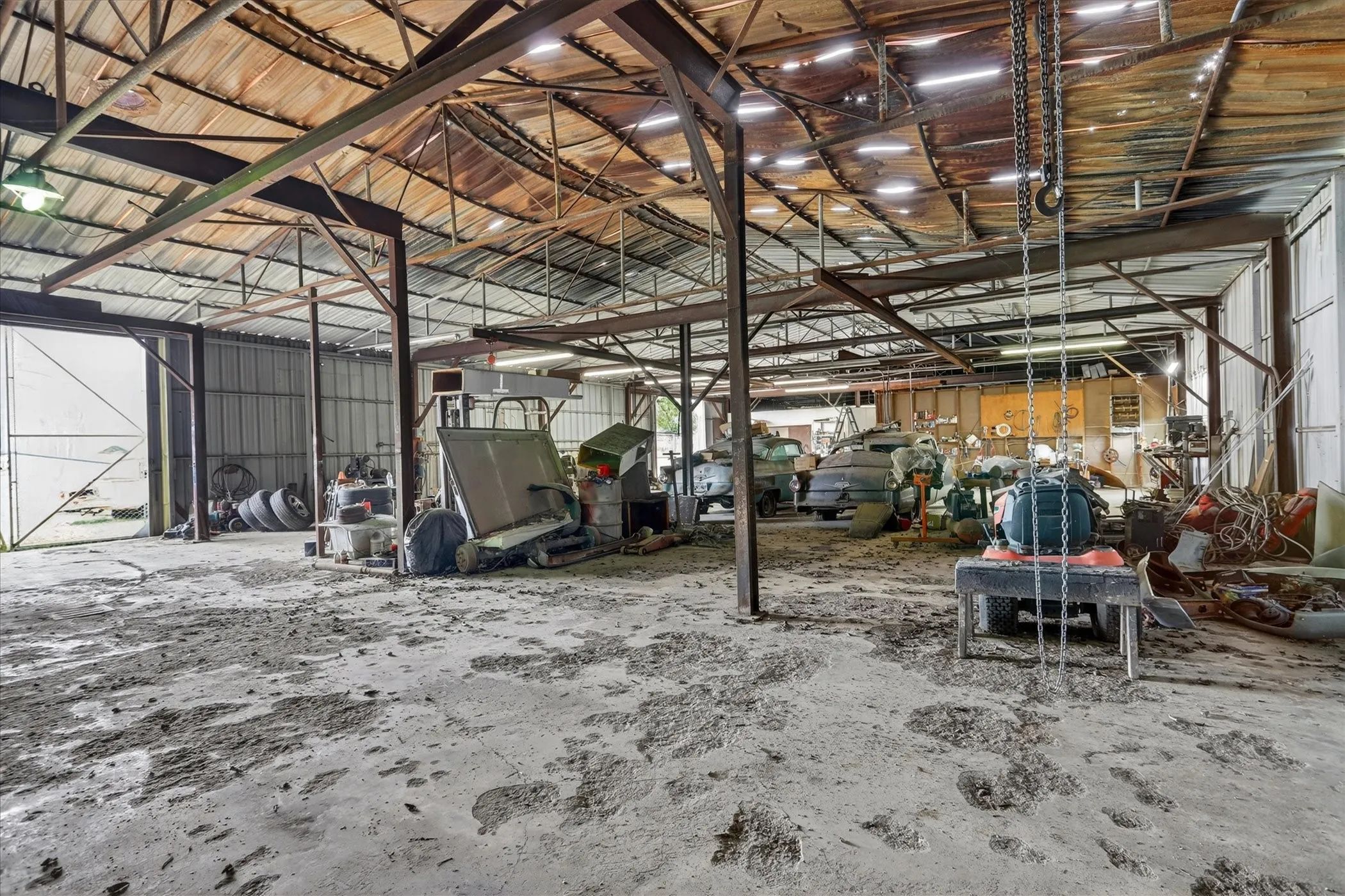 Spacious industrial building featuring exposed metal beam construction, concrete flooring, and multiple bay doors