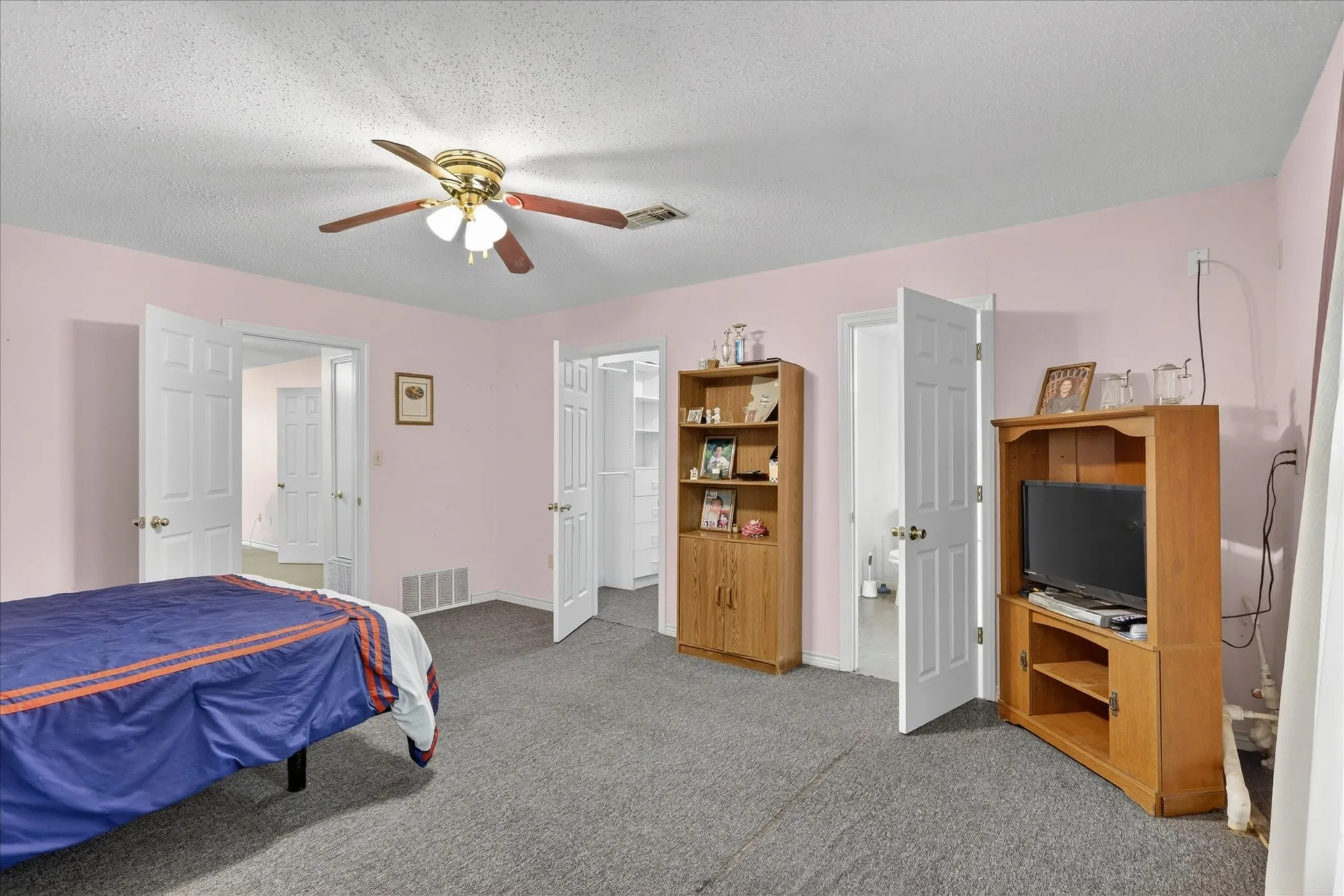 Spacious interior room with a closet, ensuite bathroom and gray carpet flooring
