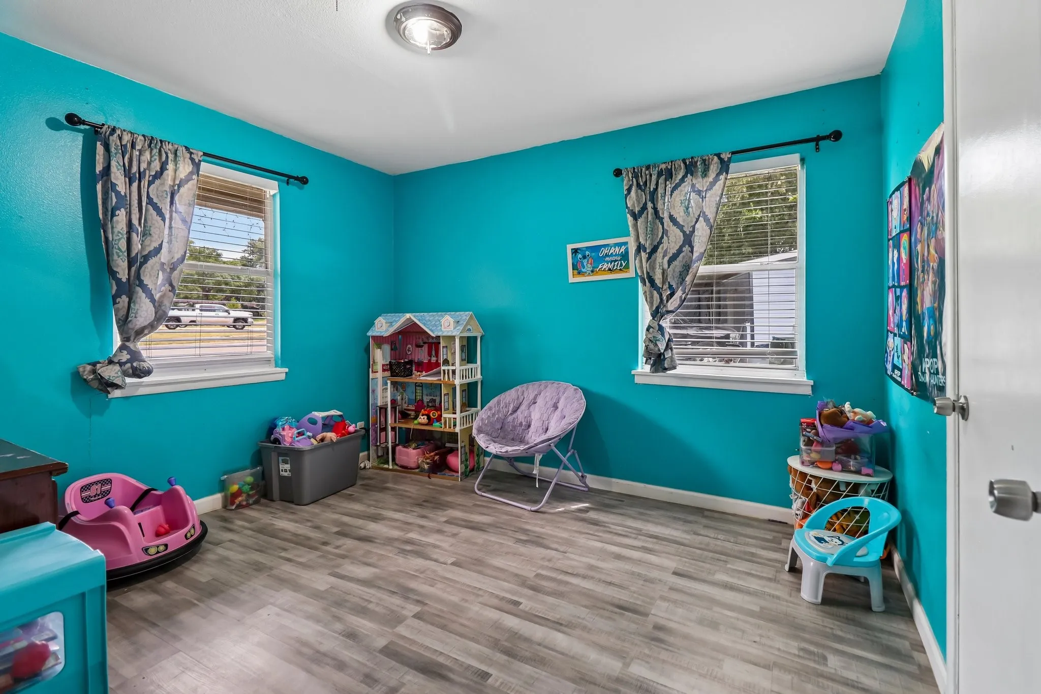 Interior room featuring wood-finish flooring, two windows, and a ceiling-mounted light fixture