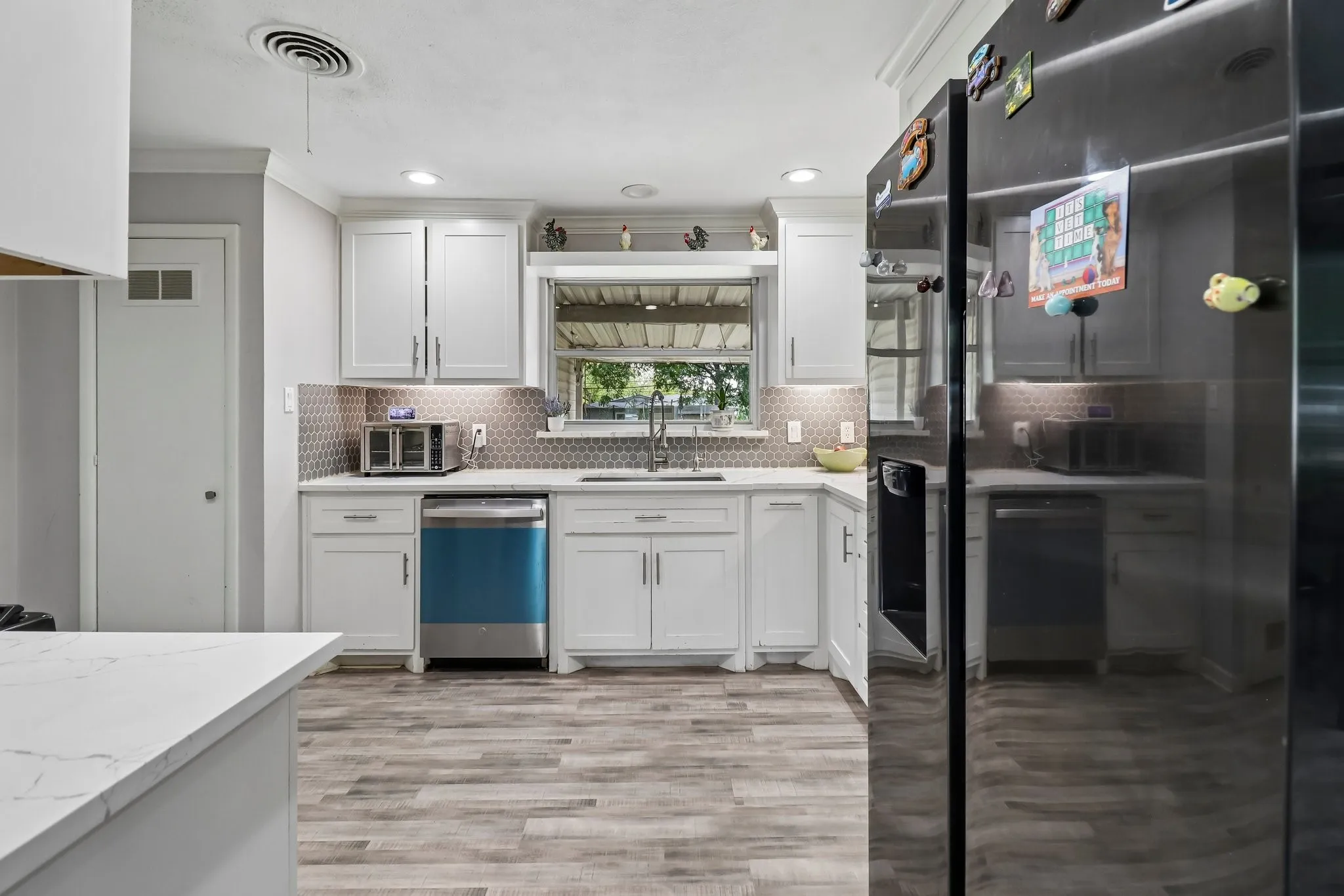 Kitchen featuring white cabinetry, wood-finish flooring, undermount sink, recessed lighting, and a patterned backsplash