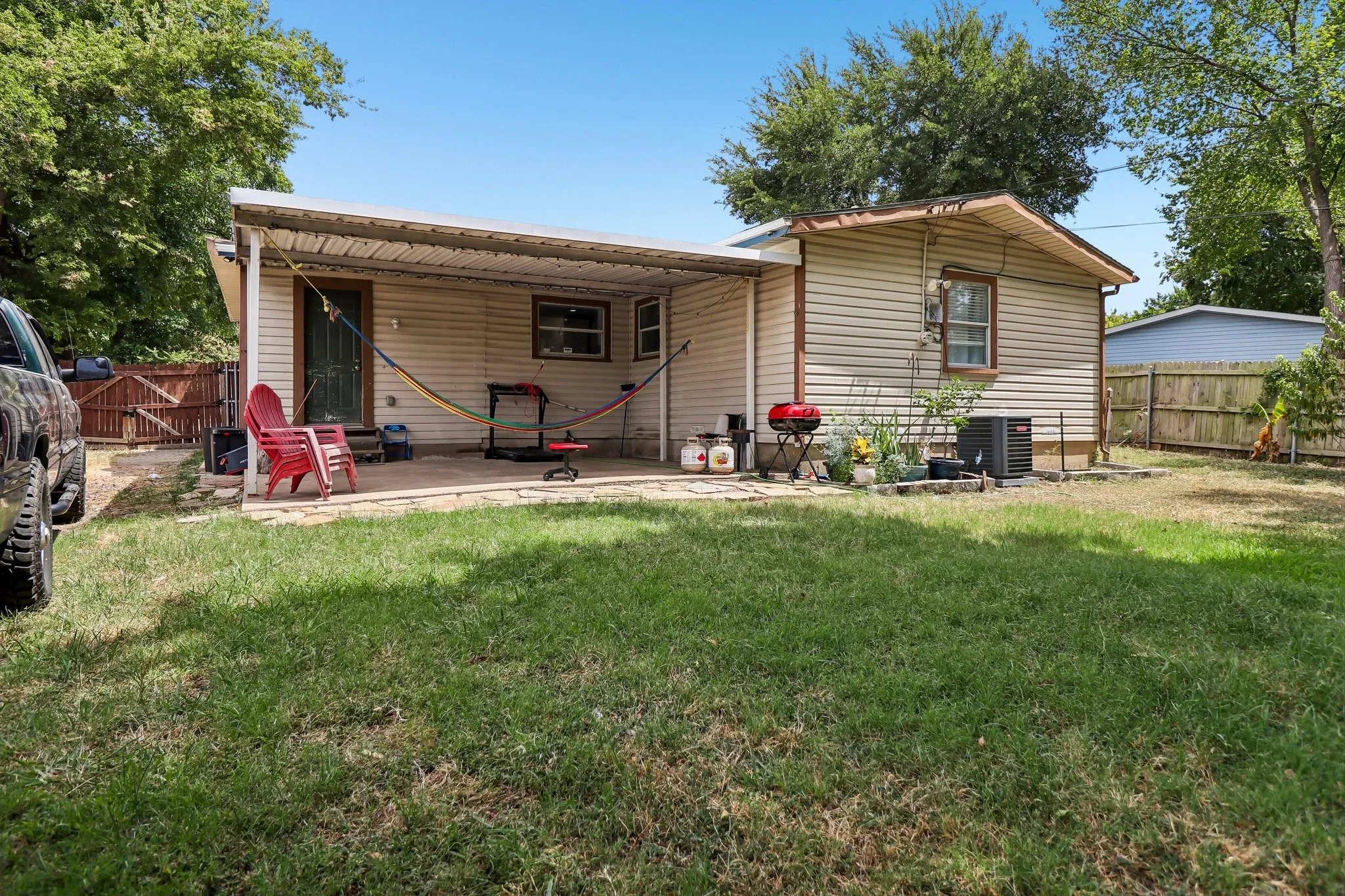 Expansive backyard featuring a covered patio, a privacy fence, and mature trees