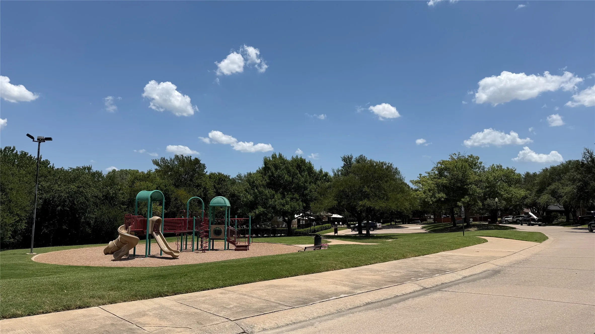 Community playground featuring multiple slides, climbing elements, and a surrounding green space