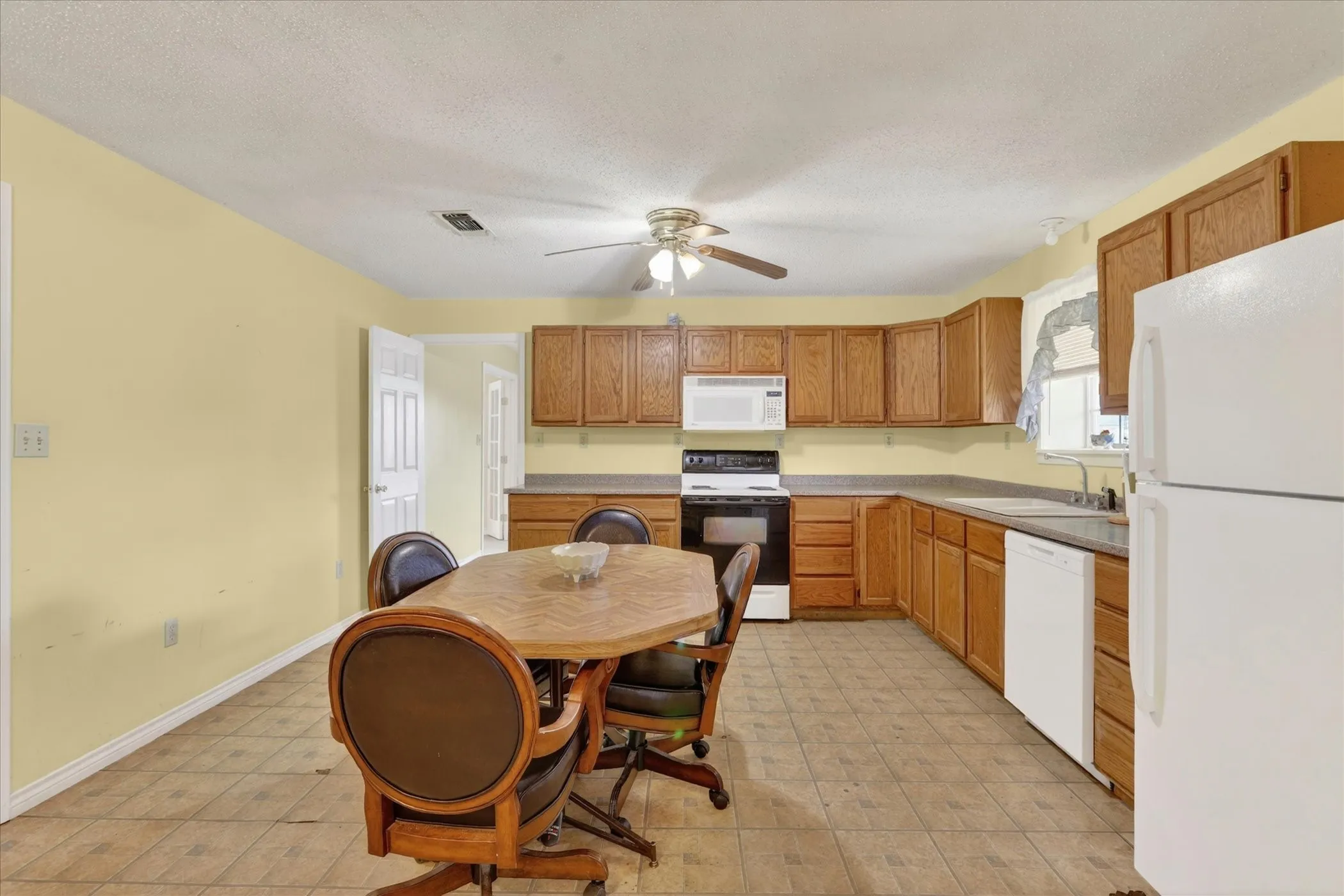 Spacious kitchen featuring a ceiling fan, wood-finish cabinetry, and white appliances