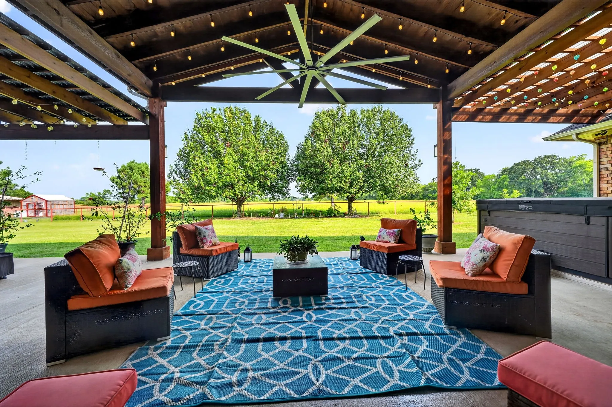 Spacious covered patio featuring a wood-beam ceiling, integrated string lighting, and a large ceiling fan