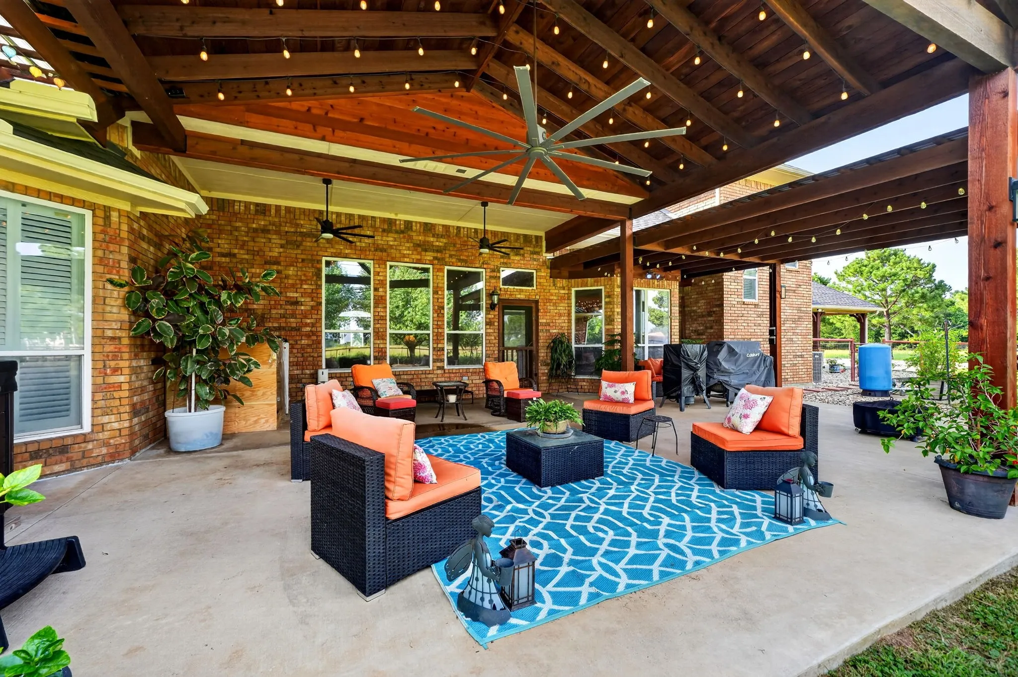 Expansive covered patio featuring a vaulted wood-beam ceiling, integrated string lighting, and large ceiling fans
