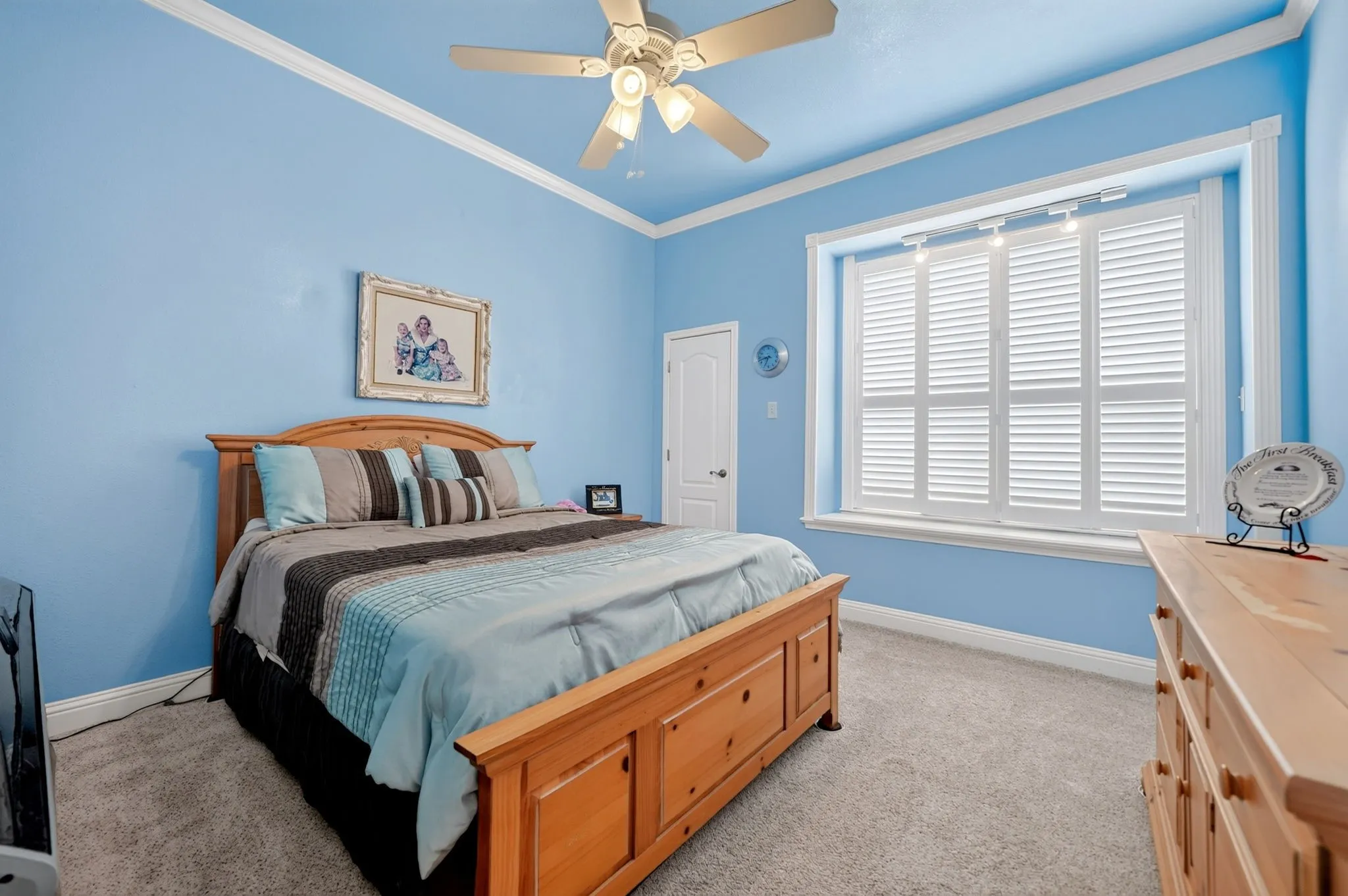 Bedroom featuring carpet flooring, a ceiling fan, crown molding, and white plantation shutters