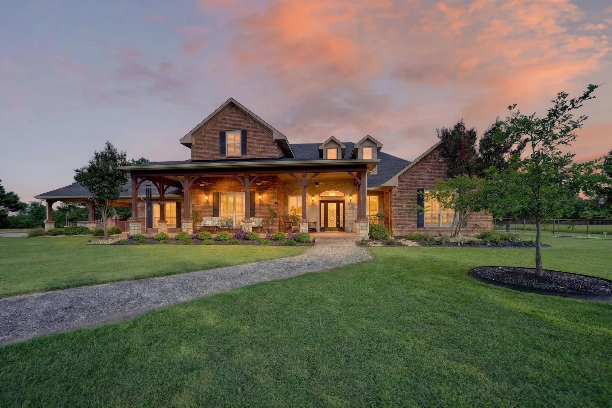 Stone and brick exterior with a deep covered porch, visible ceiling fans, and wood structural elements