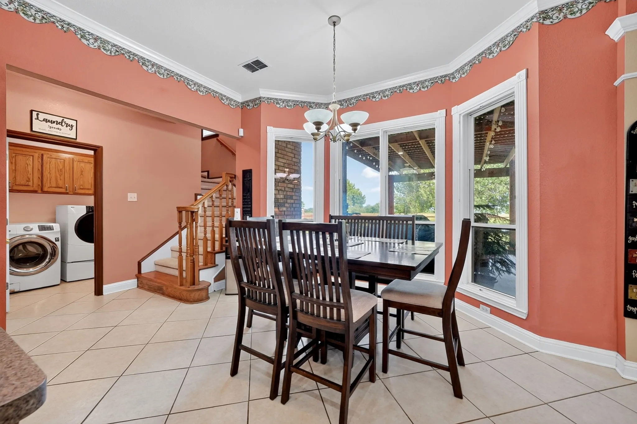 Dining area featuring three large windows, crown molding, and tiled flooring
