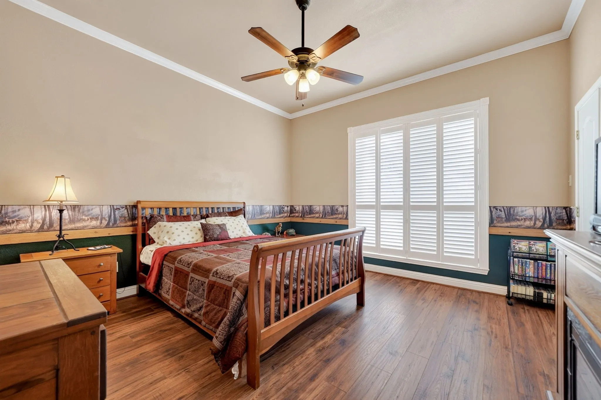Spacious room featuring wood-finish flooring, a ceiling fan with light fixture, and crown molding