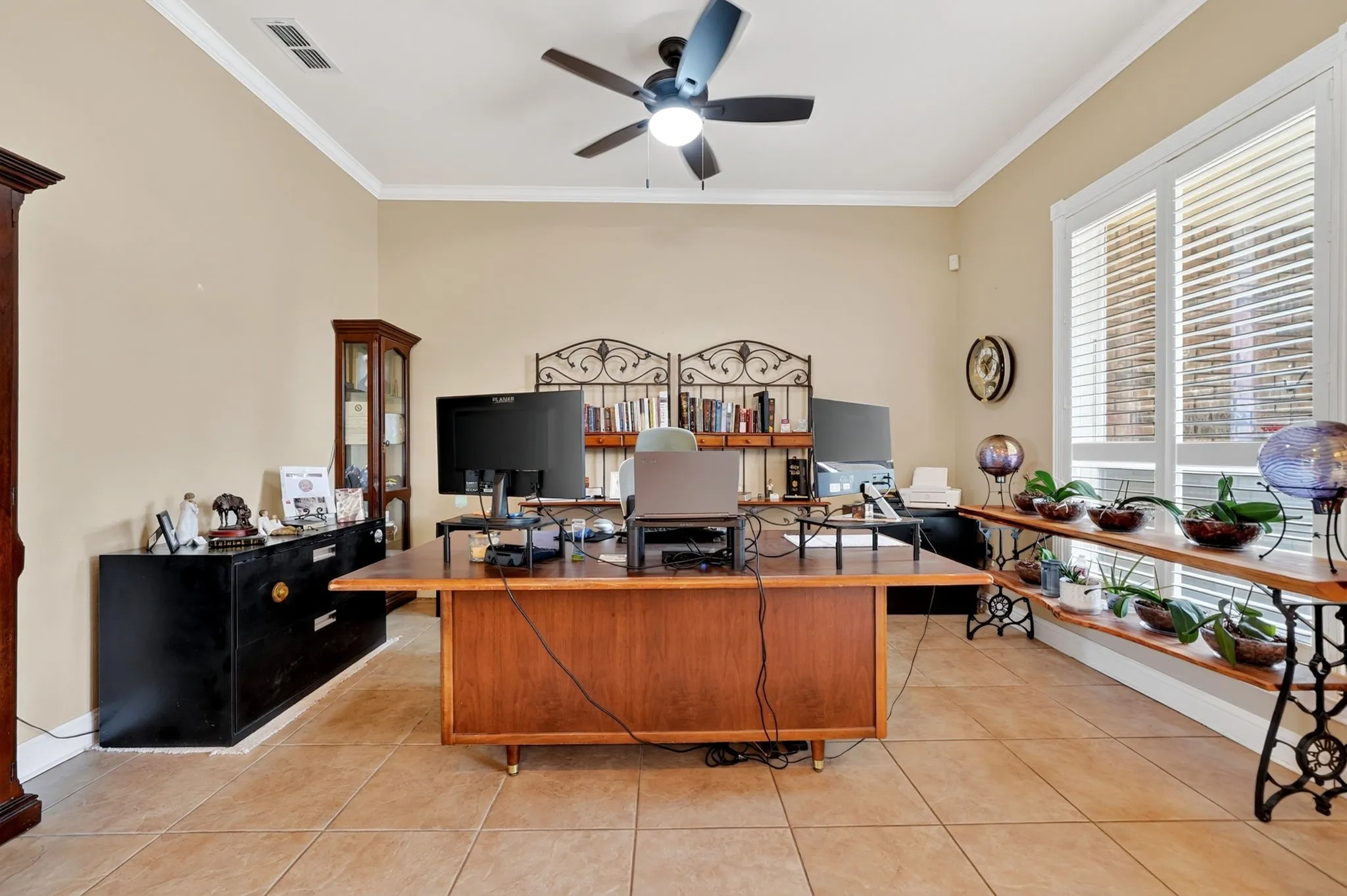 Spacious room featuring tile flooring, crown molding, and a ceiling fan