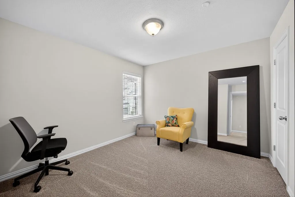 Spacious room featuring neutral wall paint, light brown carpet, and a window with horizontal blinds