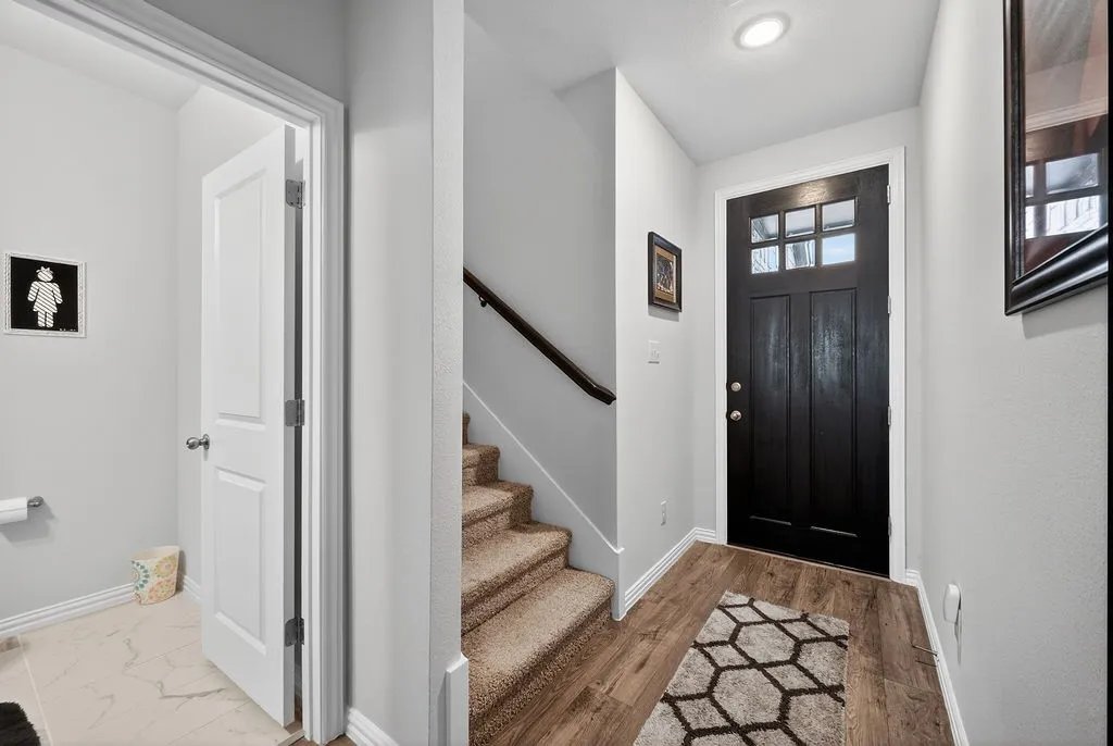 Welcoming entry featuring a dark-finish front door with glass panels, wood-finish flooring, recessed lighting, and a staircase with carpeting and a dark wood handrail