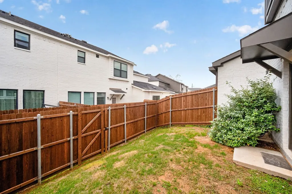 Private backyard featuring a wood privacy fence, a grass lawn, and mature shrubs
