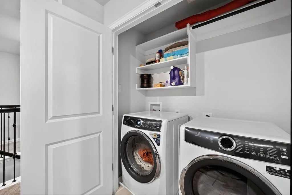 Dedicated laundry closet featuring built-in shelving, a clothes hanging bar, and appliance hookups