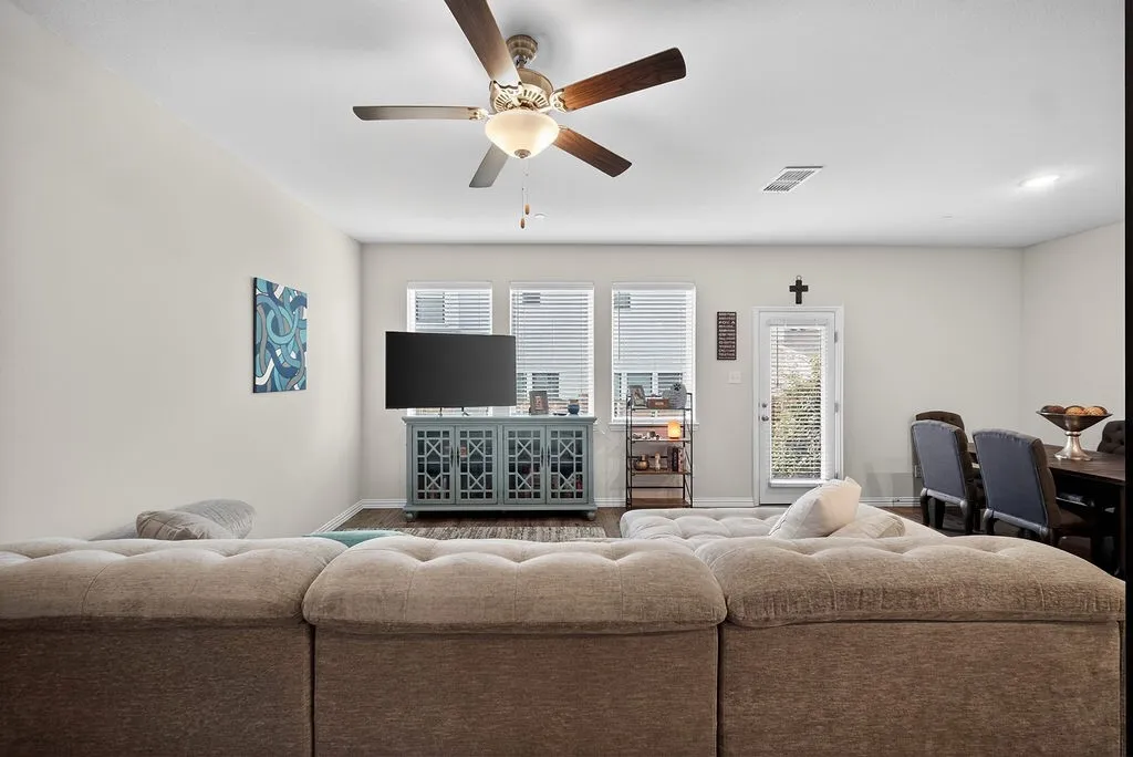 Living area featuring a ceiling fan with integrated lighting, wood-finish flooring, and light-toned walls