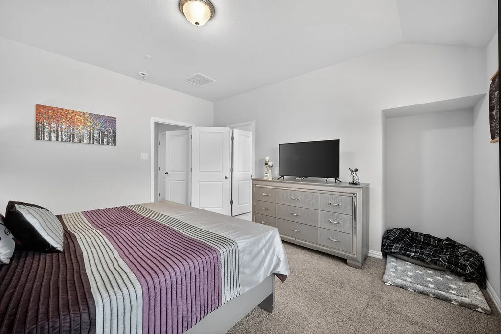 Spacious room featuring vaulted ceilings, neutral-toned walls, and plush carpet flooring