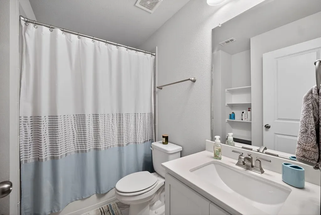 Bathroom featuring a white vanity with an integrated sink, silver-toned faucet, and a large wall-mounted mirror