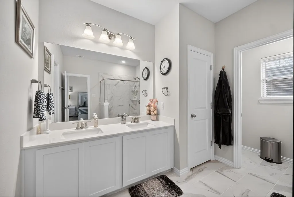 Double vanity with white cabinetry, quartz-finish countertop, and undermount sinks