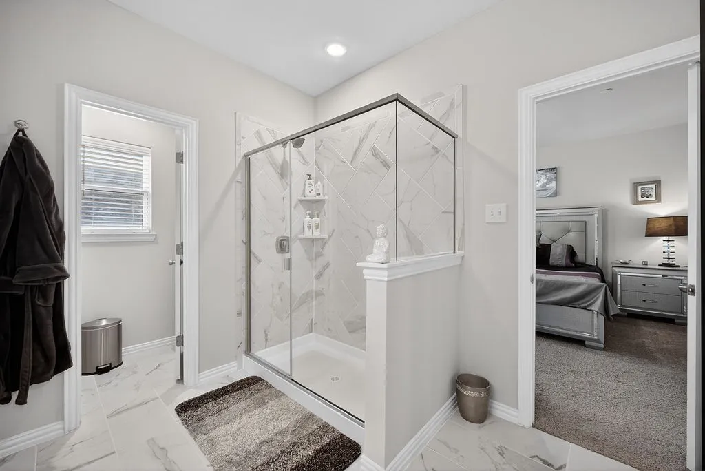 Glass-enclosed shower featuring white and gray patterned tile, an integrated shower niche, and a white shower pan
