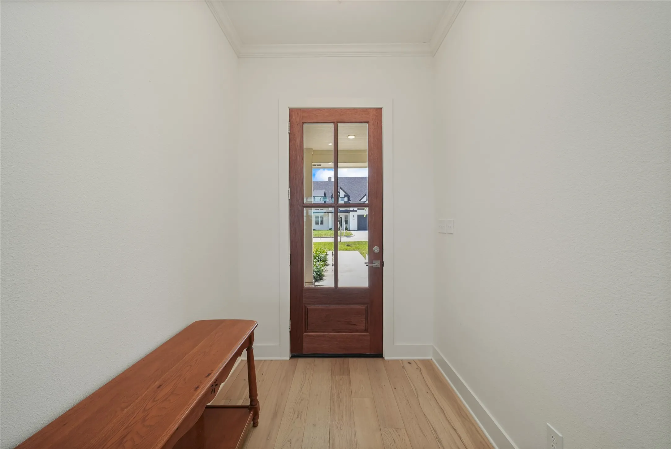 Entryway featuring a rich wood-finish door with multiple glass panes, light wood-finish flooring, and crisp white trim