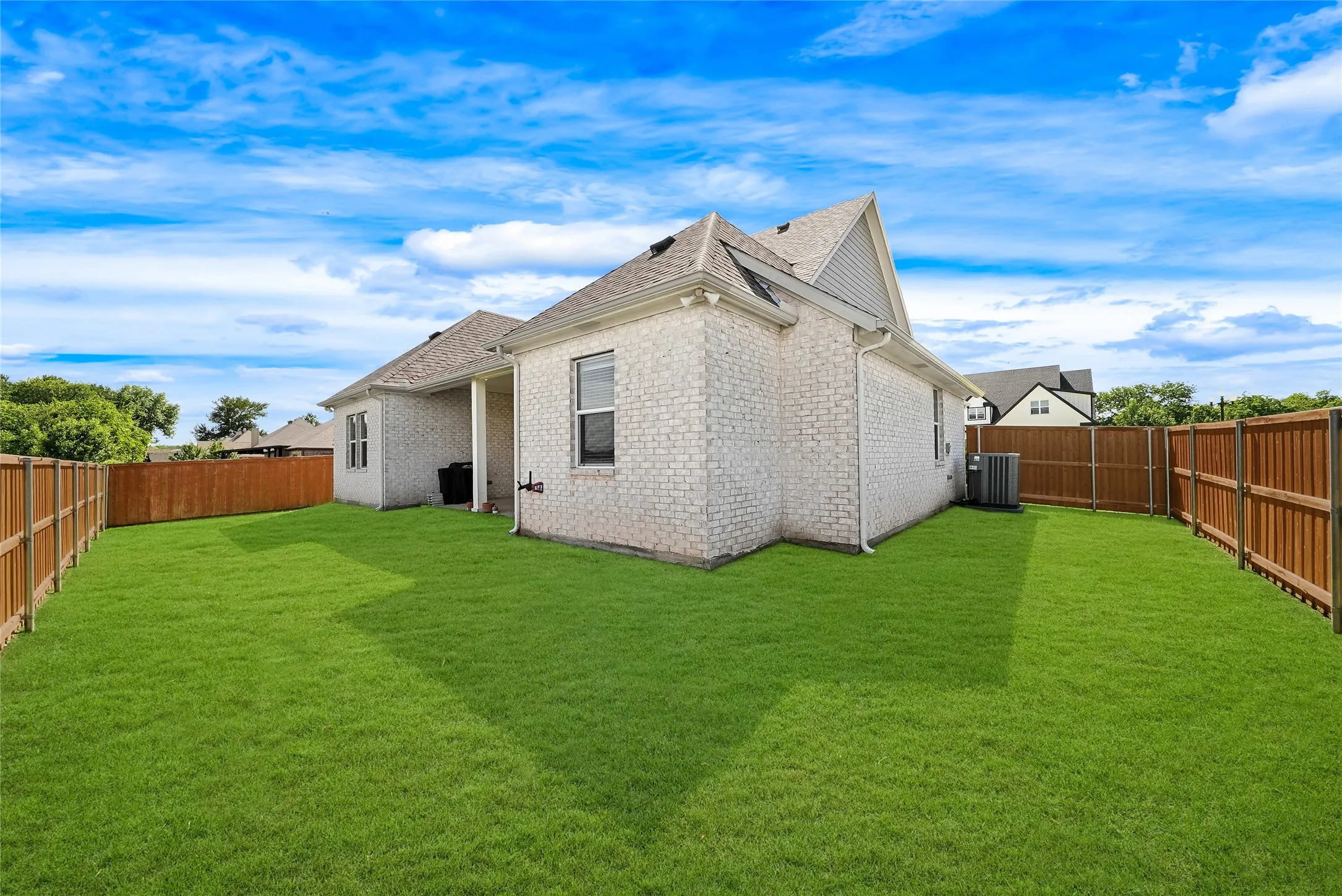 Expansive backyard featuring a lush green lawn and new wood fencing