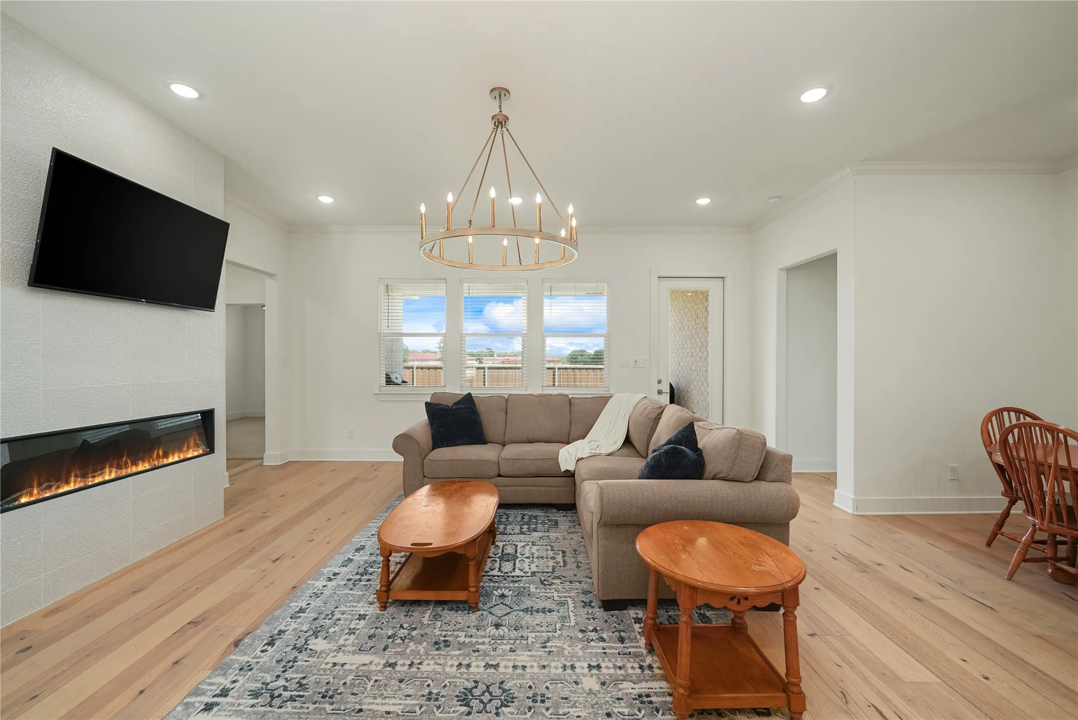 Open-concept living space featuring wood-finish flooring, a linear electric fireplace with a tiled surround, and recessed lighting