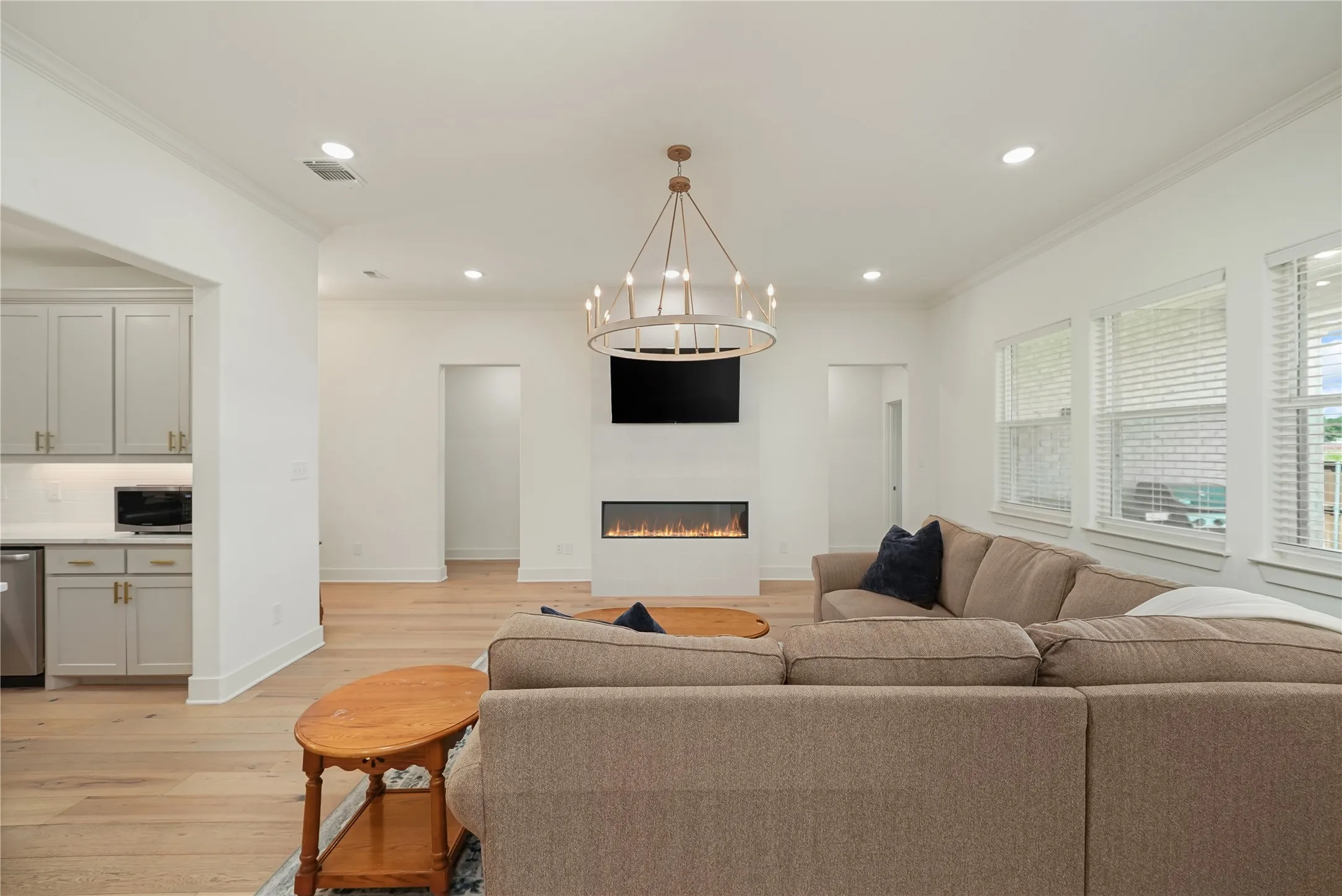 Spacious living area featuring light wood-finish flooring, a contemporary linear fireplace, and recessed lighting