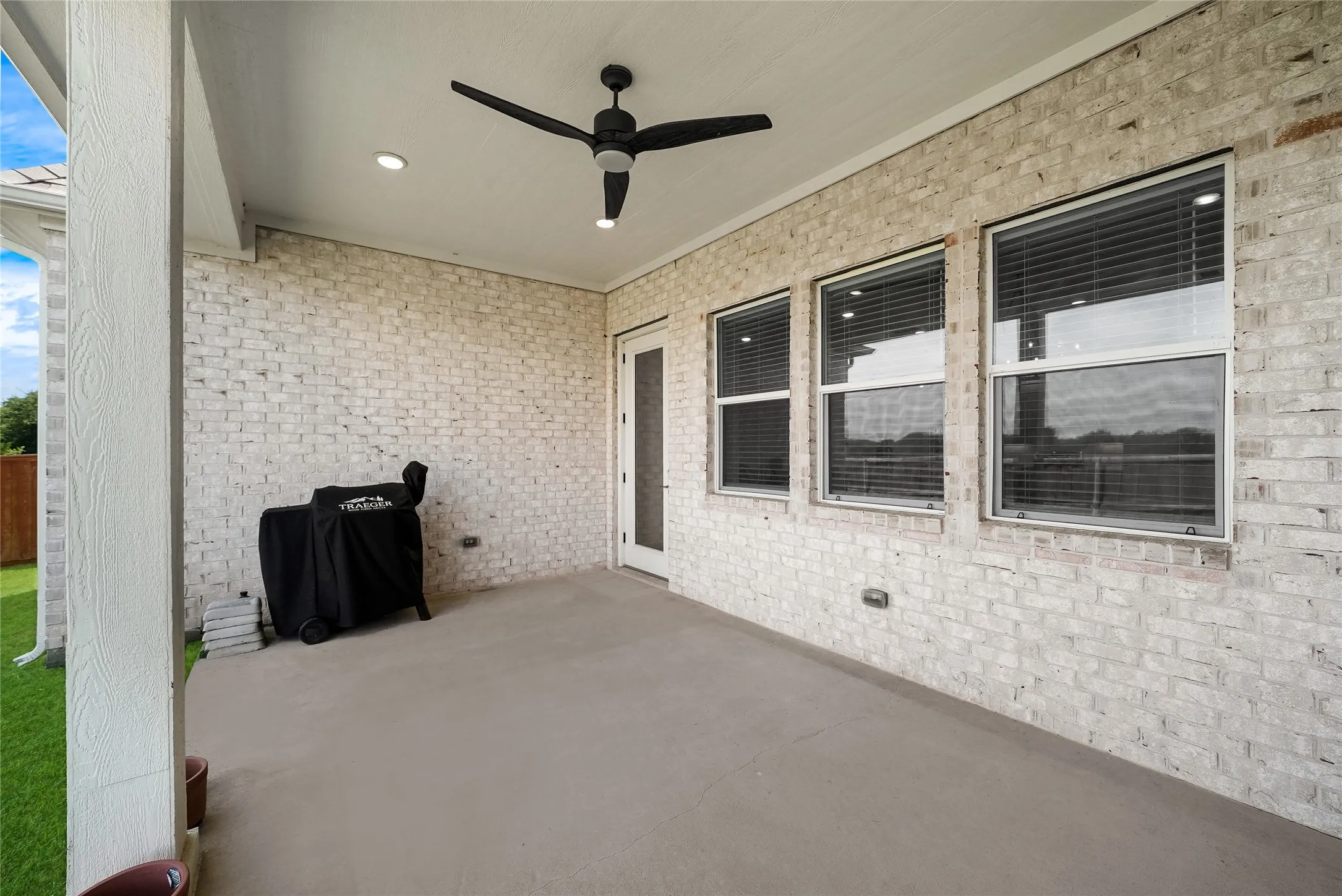 Covered patio featuring a concrete slab, white brick exterior wall, recessed lighting, and a ceiling fan