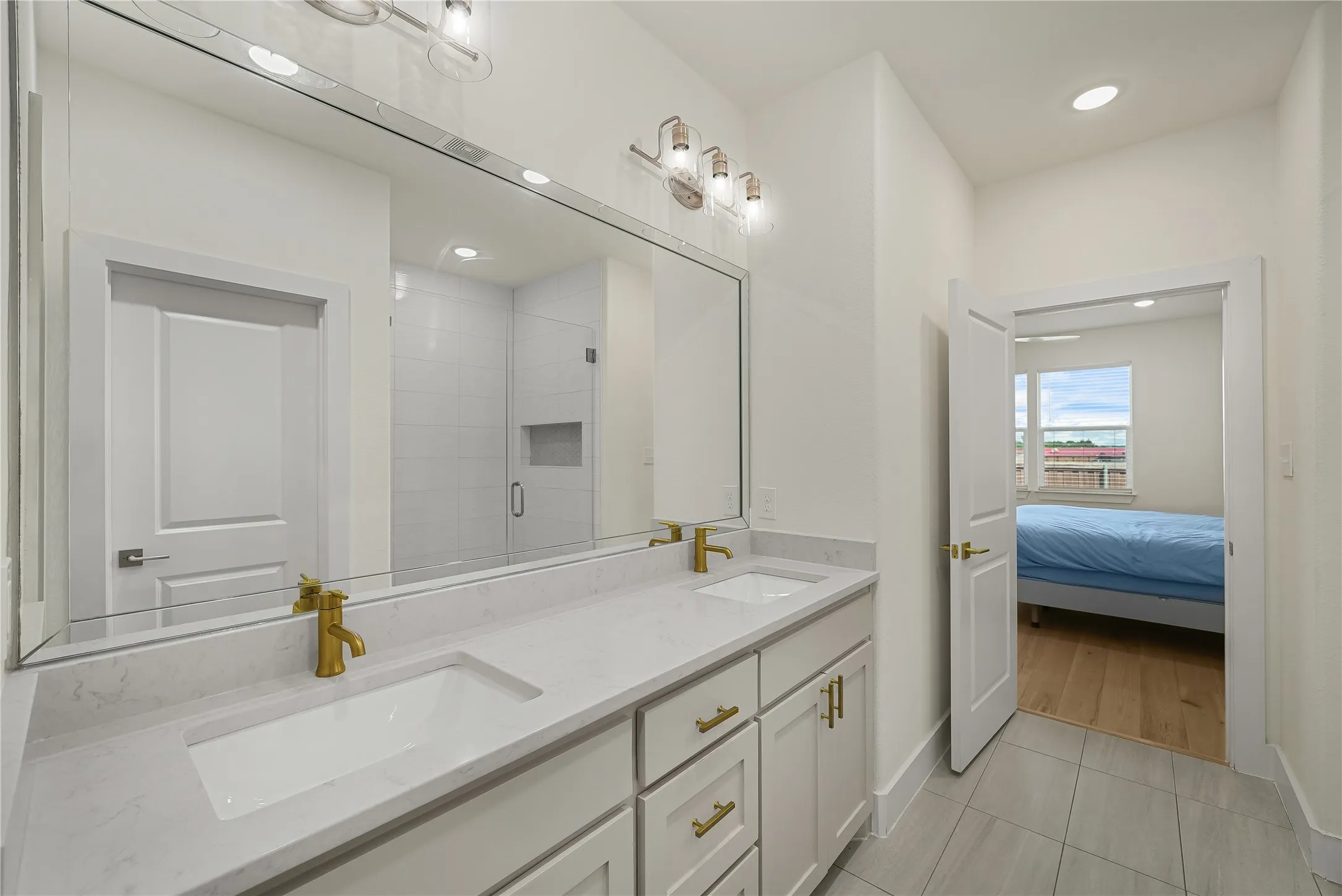 Bathroom featuring a double vanity with stone countertops, undermount sinks, and gold-finish fixtures