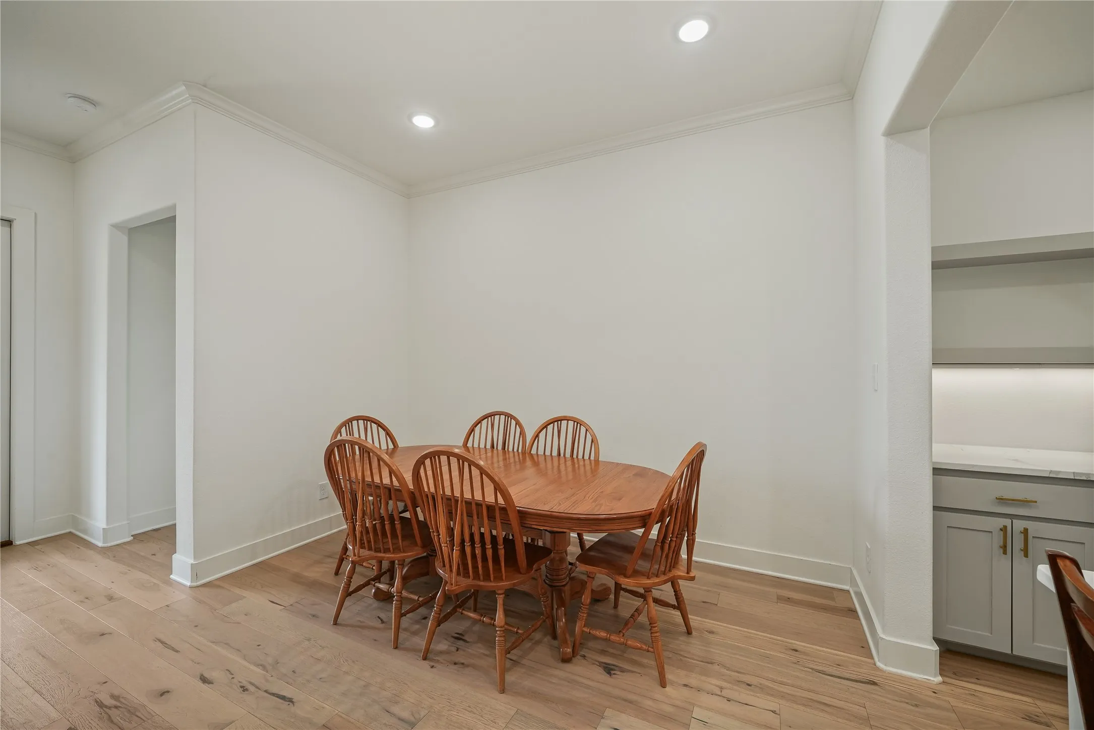 Dining area with wood-finish flooring, recessed lighting, and crown molding