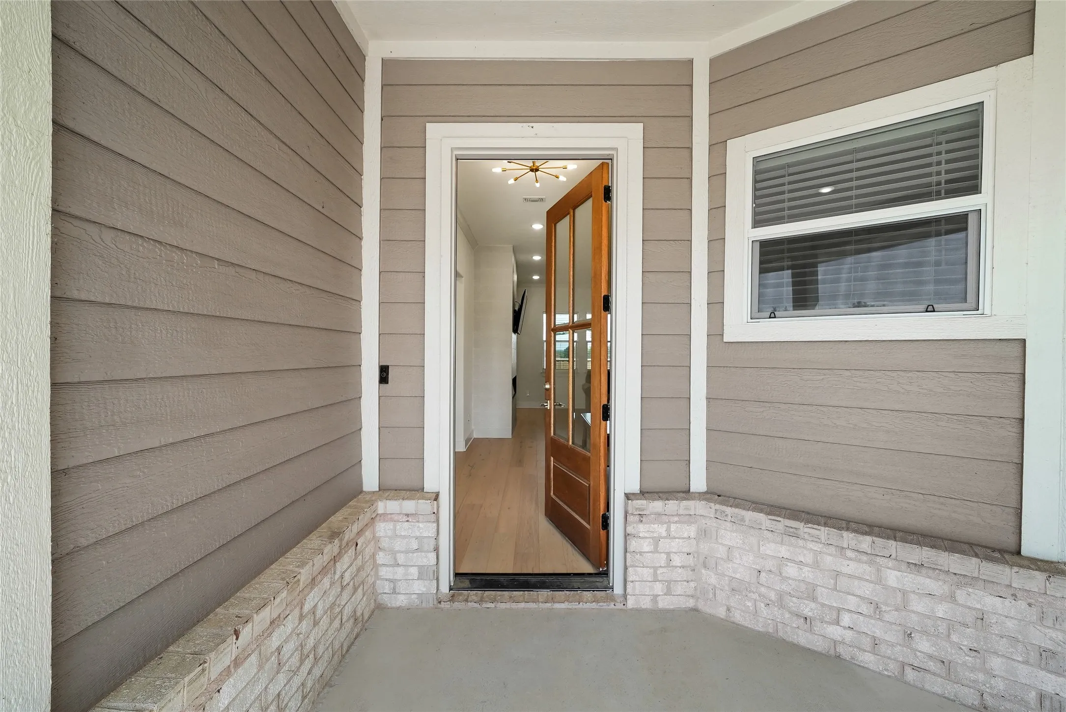 Inviting entryway featuring a wood-panel and glass-paneled door, horizontal siding, and a partial brick facade
