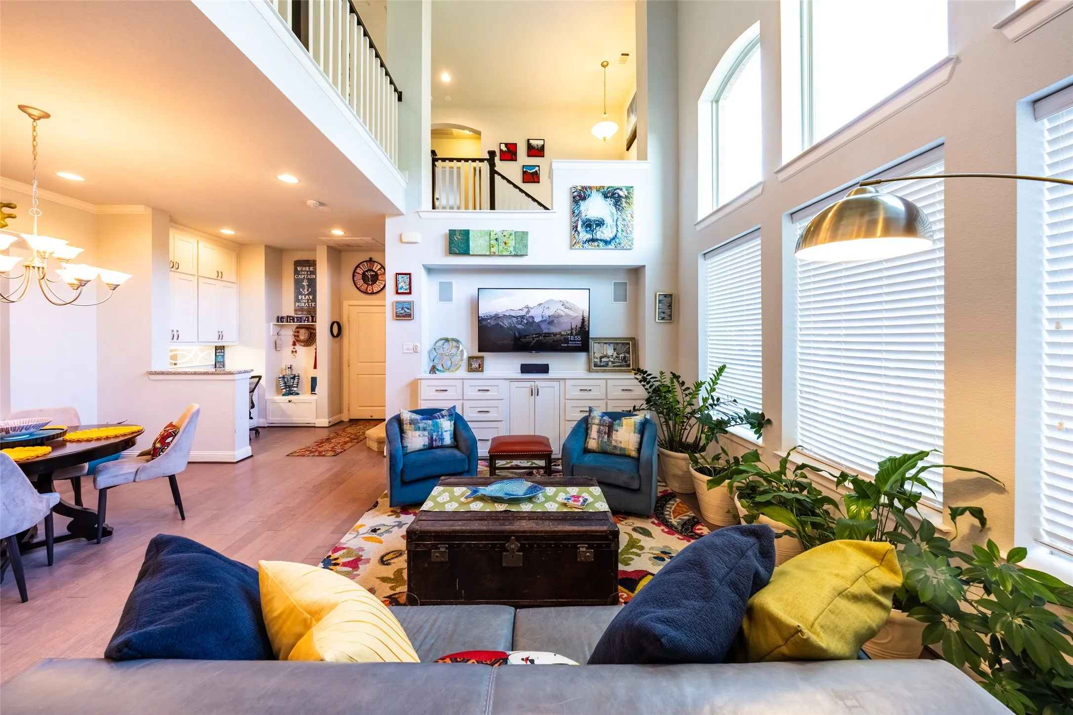Spacious living area viewed from entry way and showing an upper-level balcony with white balusters