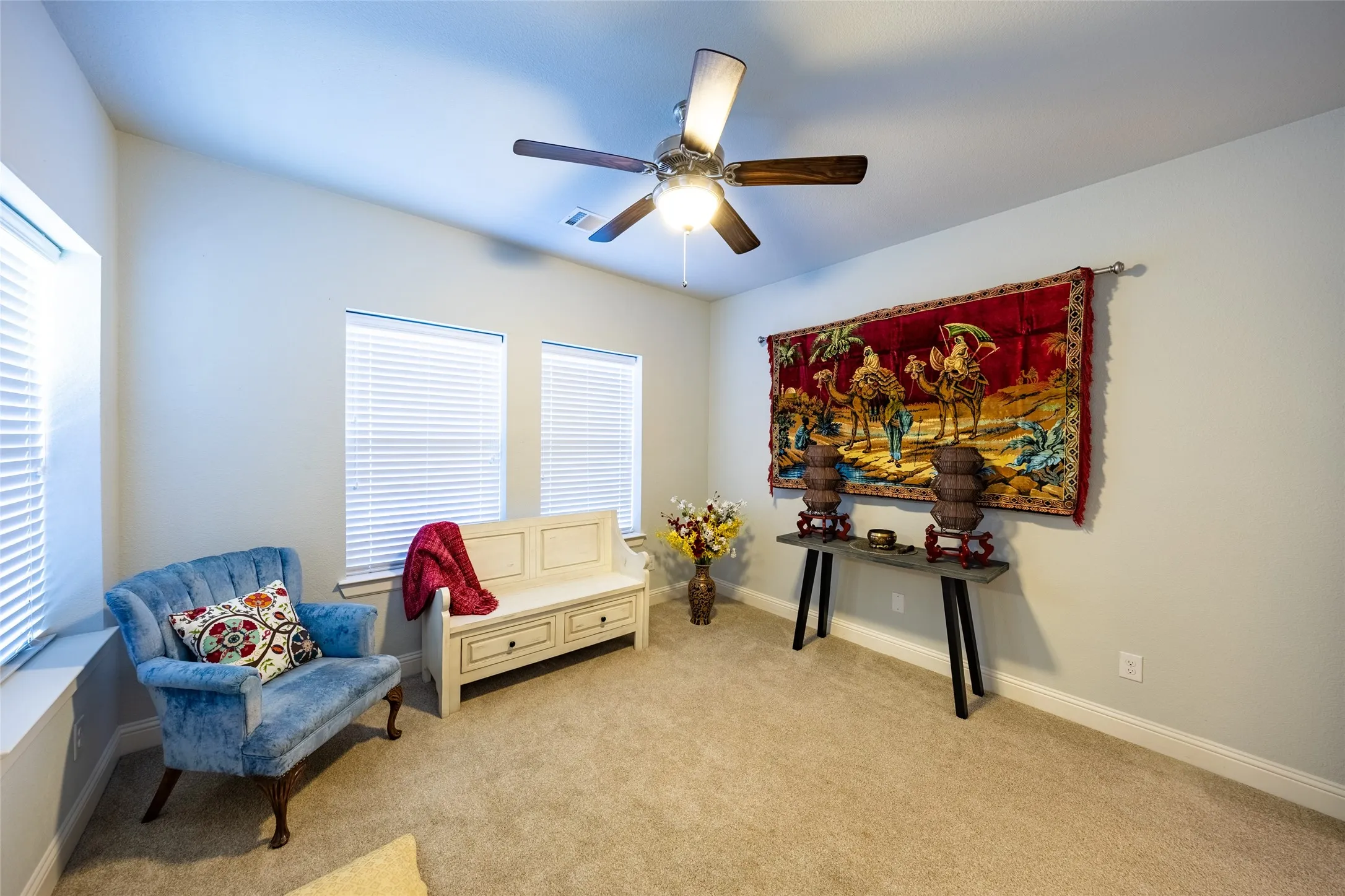 Yoga or guest room with numerous windows and ceiling fan.