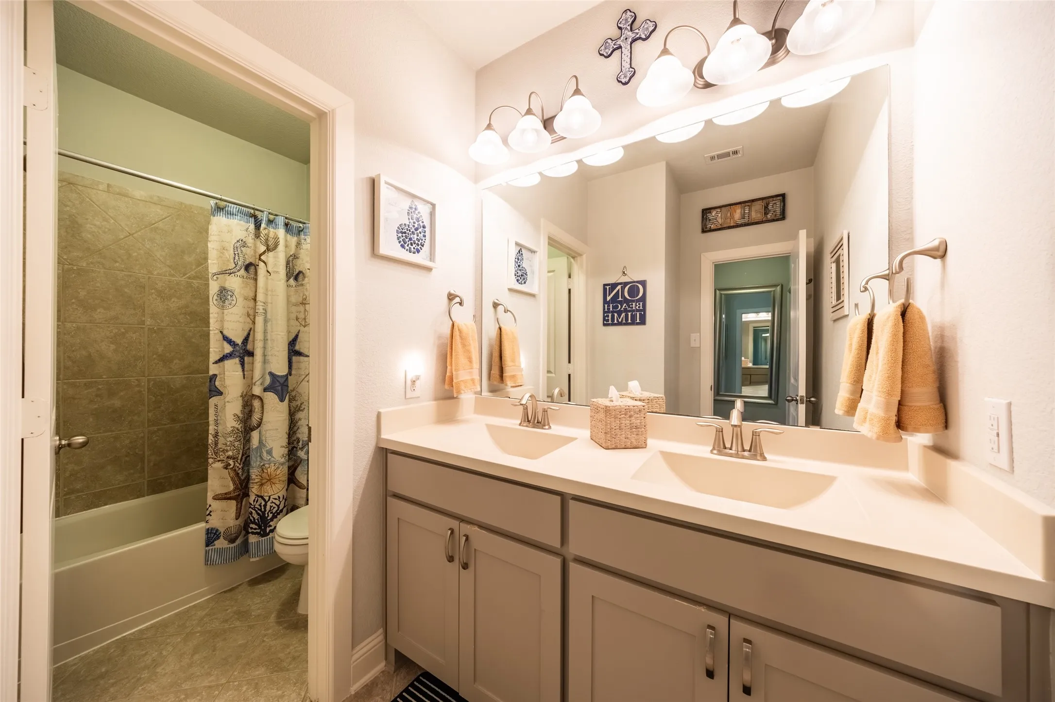 Guest bathroom featuring a dual-sink vanity with light-toned countertops and under-sink cabinetry