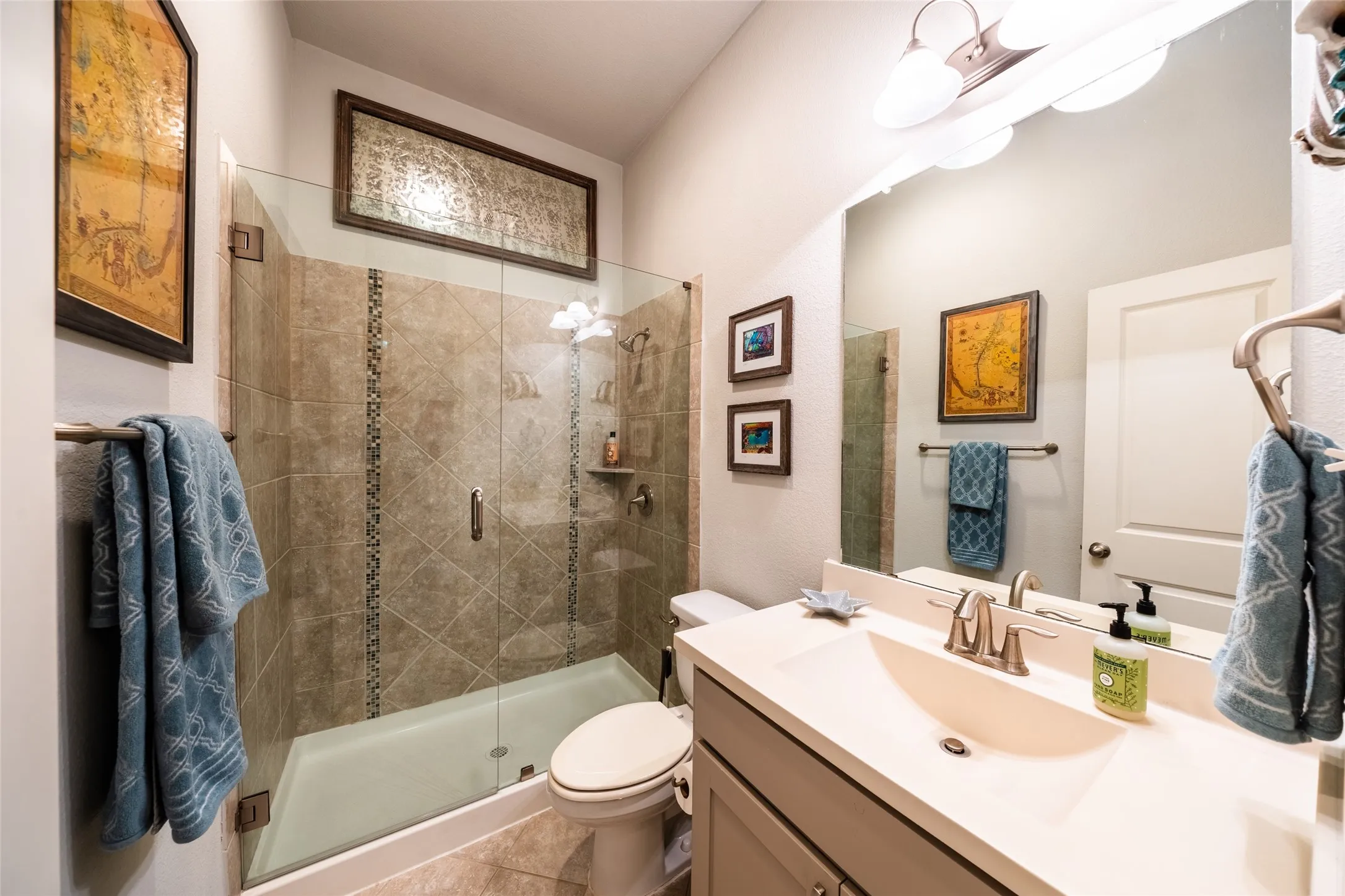 Downstairs bathroom featuring a glass-enclosed shower with tile surround, a single vanity with an integrated sink