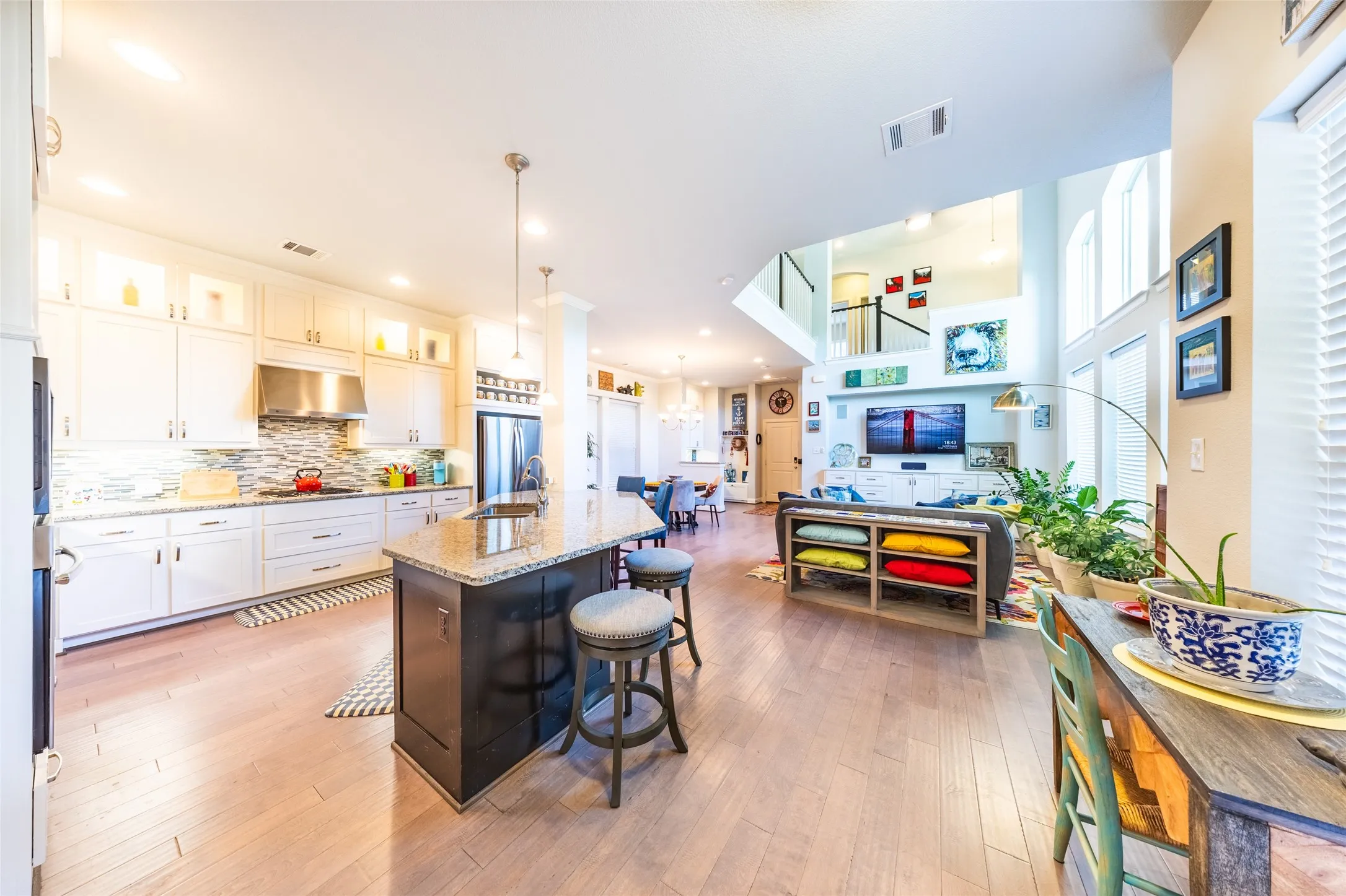 Open-concept living area featuring light wood-finish flooring, a two-story ceiling, and extensive natural light