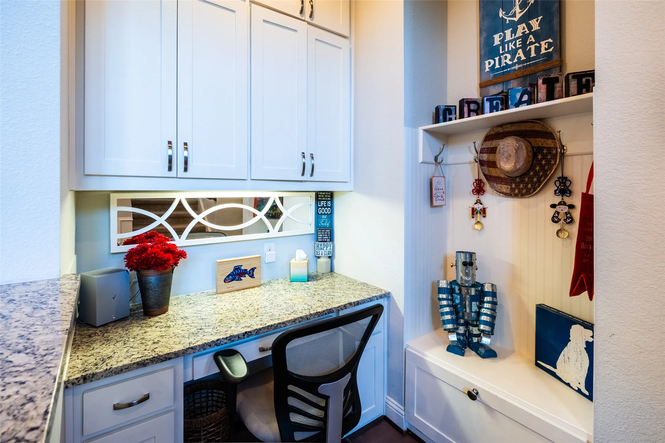 Built-in desk area featuring granite countertop, white cabinetry and under-cabinet lighting.  Built in custom coat rack and shoe cubby.