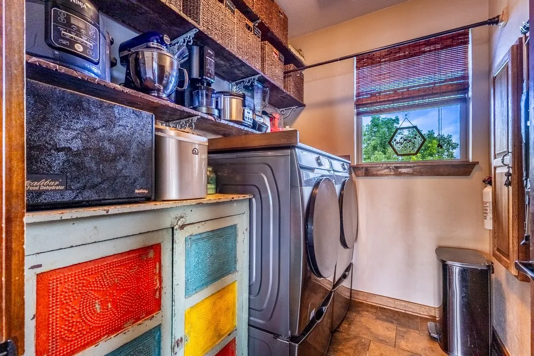 Laundry room with tons of storage, window for natural light, convenient hanging rod, & fold down ironing board.