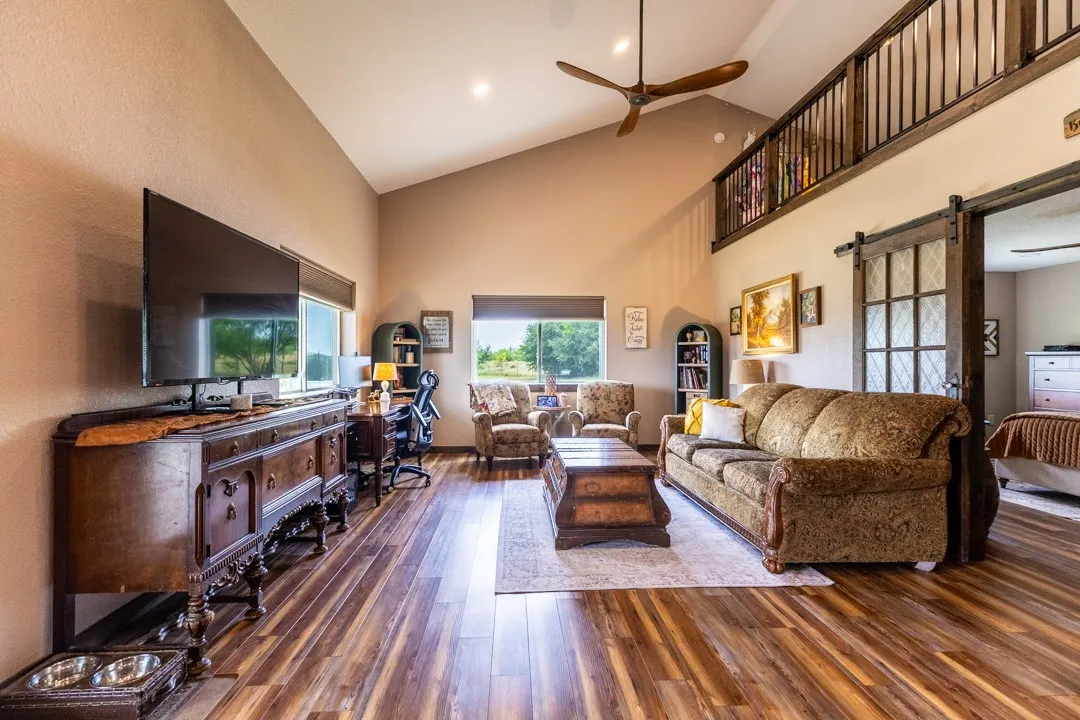 Living area with barn door entry into the bedroom and loft above; windows allow a view towards the playground.