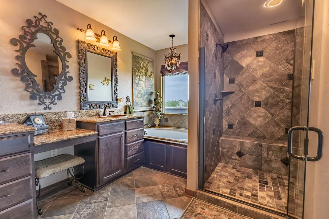 Beautiful tile, granite, warm wood, and natural light from the window above the tub.