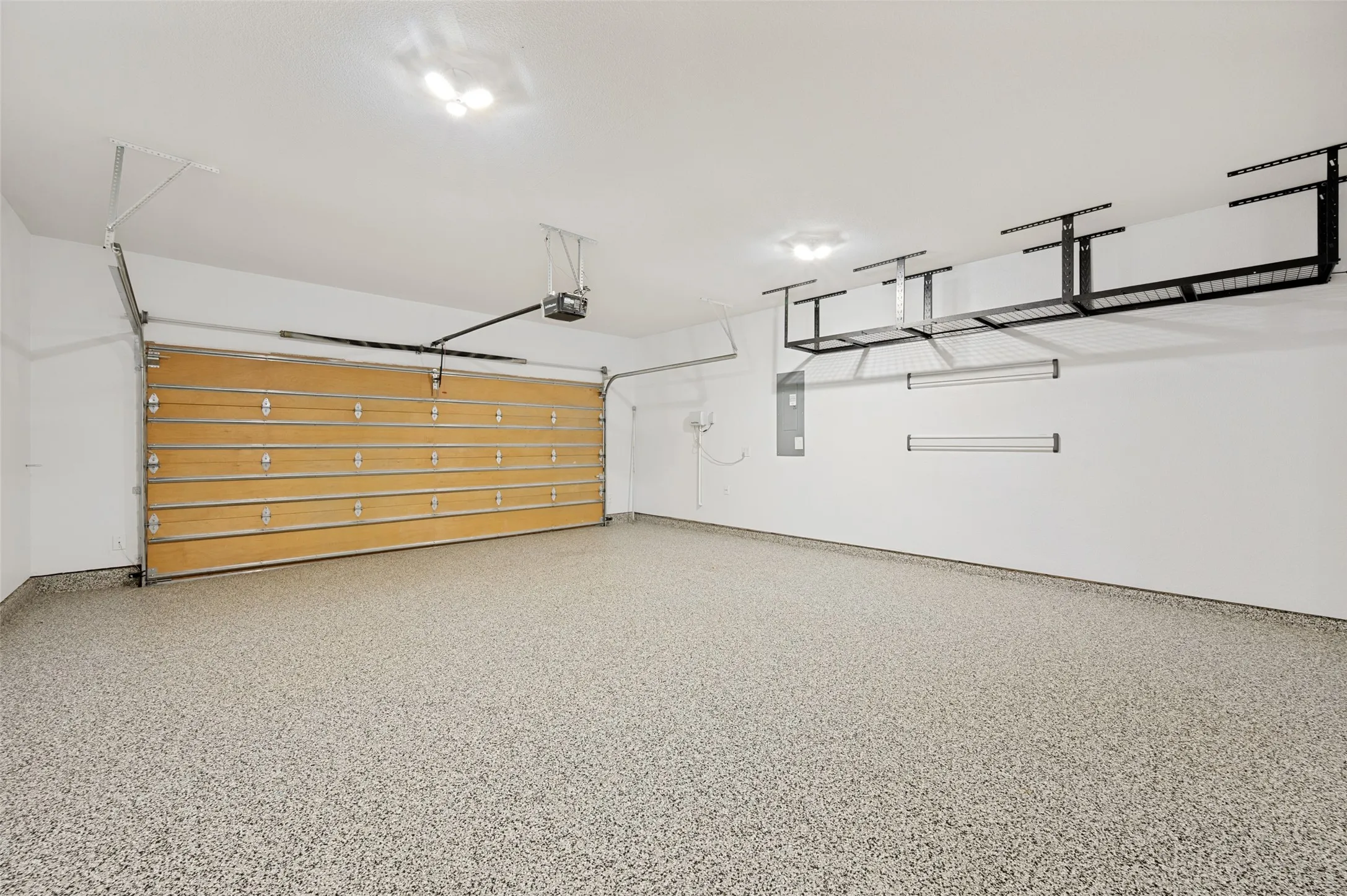 Spacious 2 car garage featuring a durable epoxy-coated floor, and overhead storage racks.