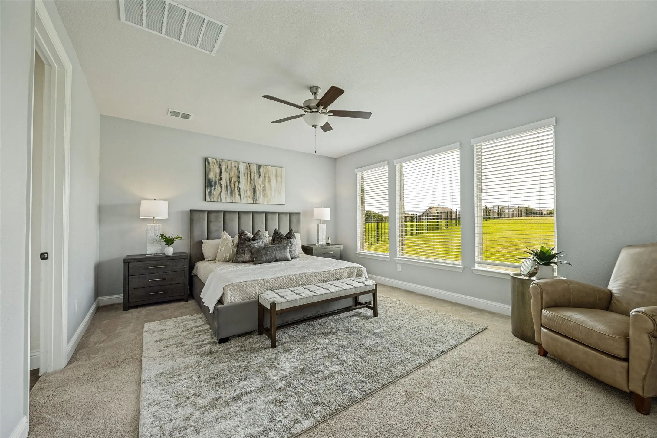 Carpeted room featuring a ceiling fan, three large windows with horizontal blinds, recessed lighting, and a neutral wall color