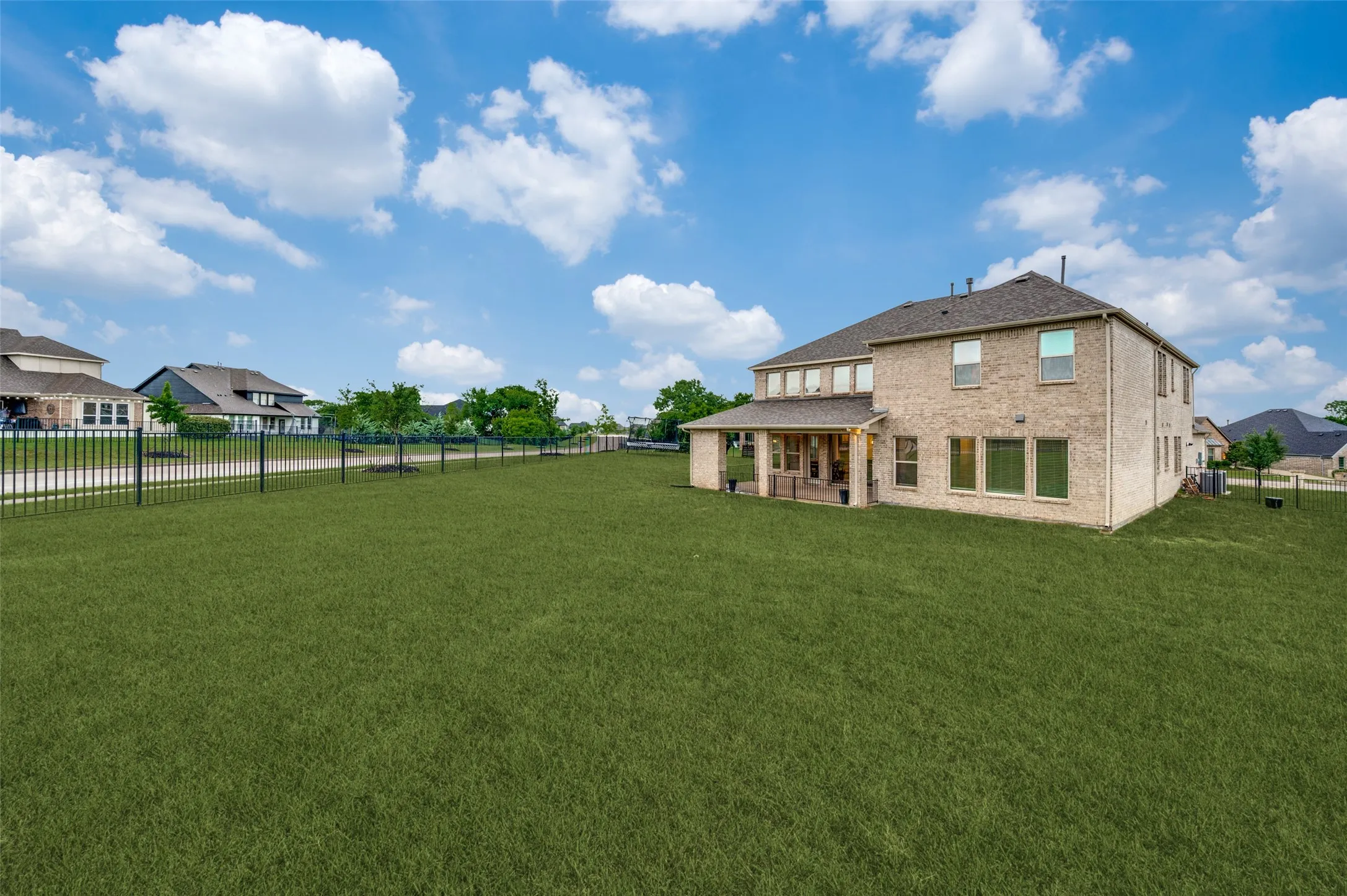 Expansive grass lawn featuring a black metal fence