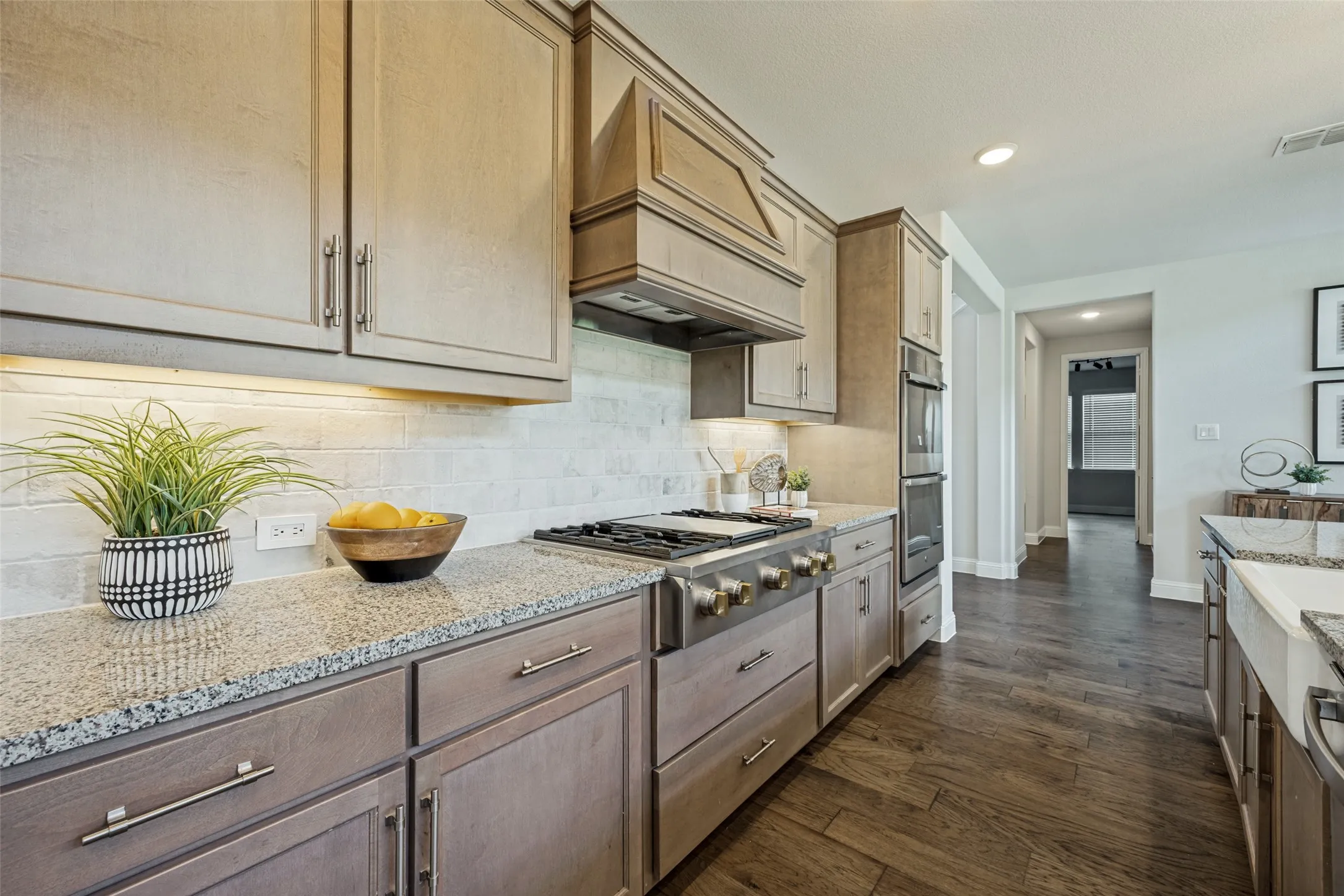Kitchen featuring wood-finish flooring, light grey cabinetry, granite countertops, and a subway tile backsplash