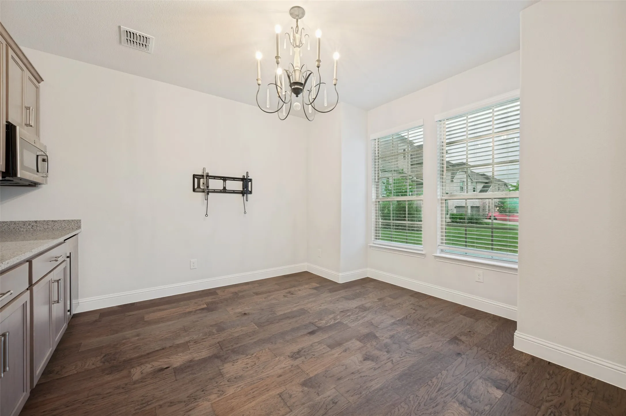 Multi-generational kitchenette featuring wood-finish flooring, a contemporary chandelier, and two large windows with horizontal blinds. Attached to a bedroom with ensuite bathroom. Perfect for guests, or multi- generational living.
