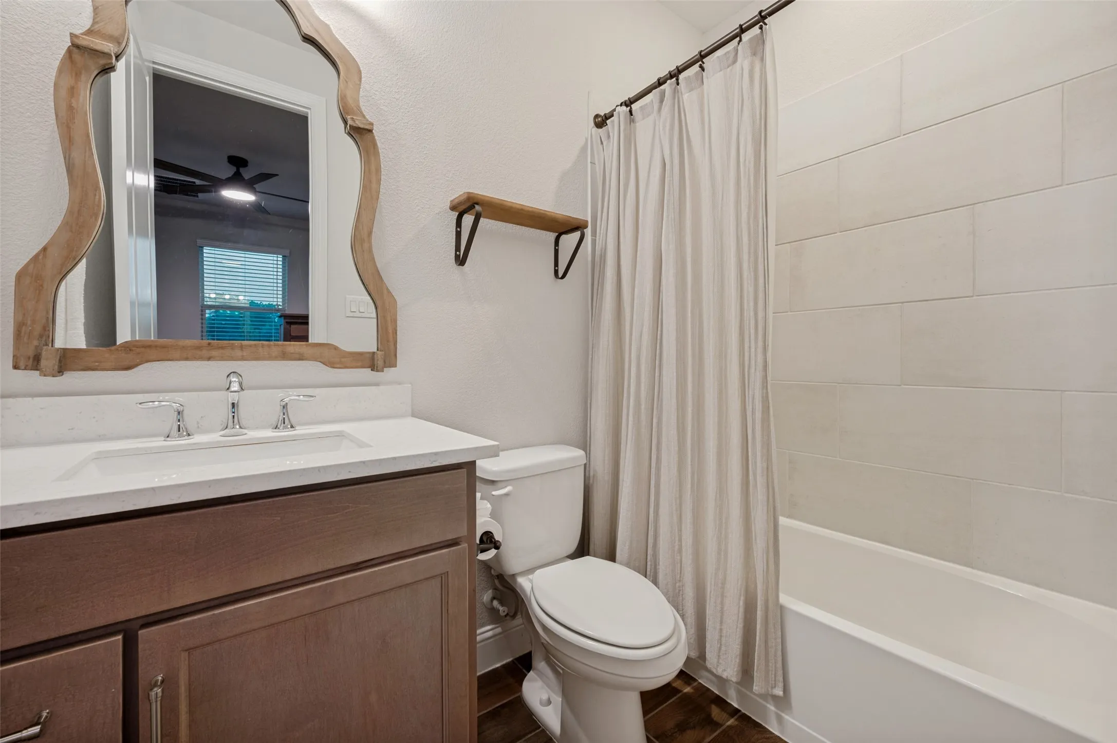 Multi- Generational ensuite bathroom featuring a wood-finish vanity with a white countertop, chrome fixtures, and a decorative mirror.