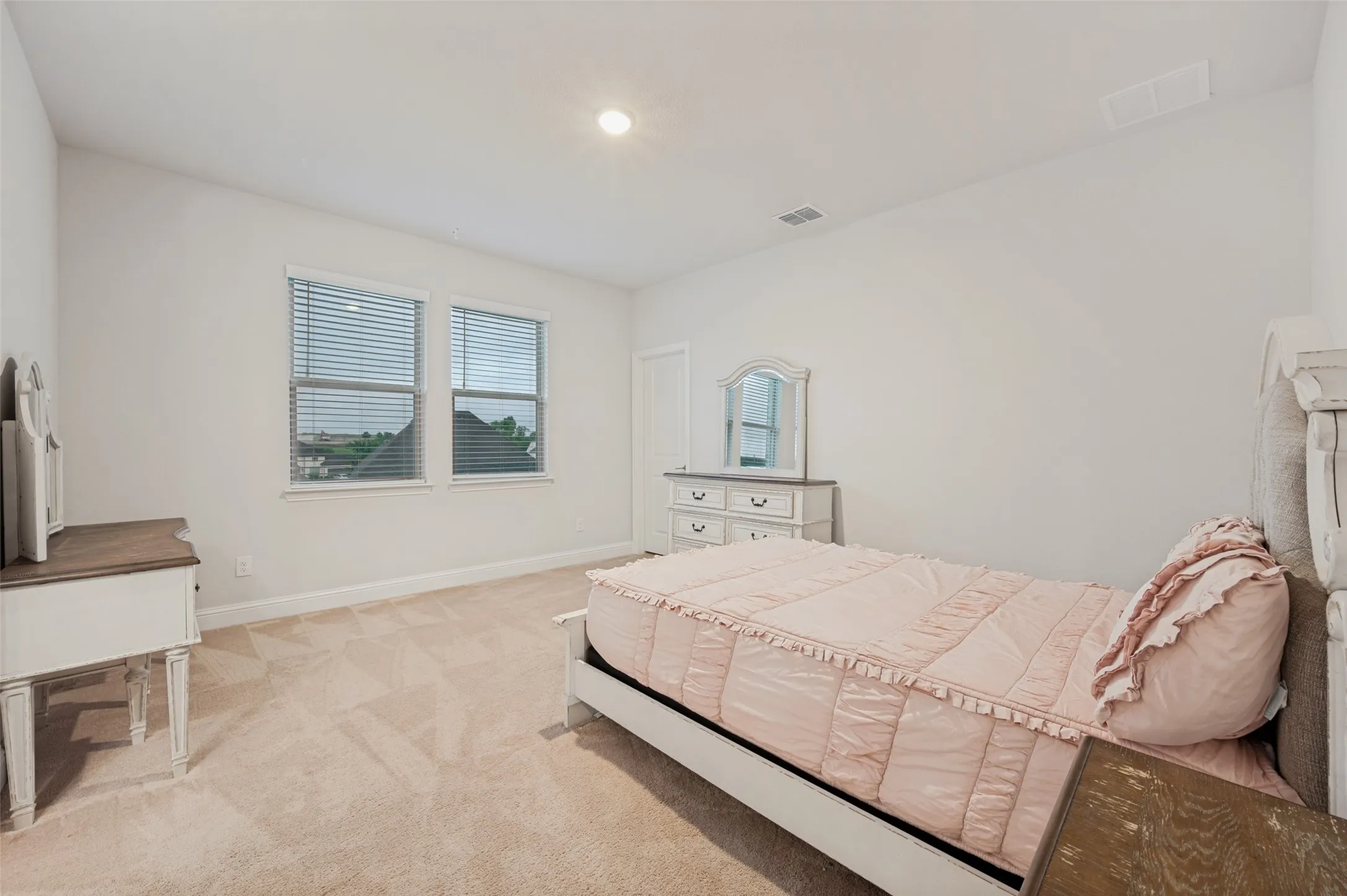 Spacious room featuring walk-in closet, neutral carpeting, two windows with horizontal blinds, and dual access bathroom.
