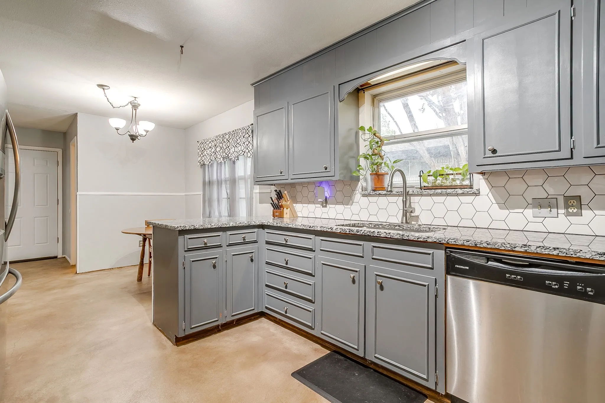 Kitchen featuring gray cabinetry, light-toned countertops, and a white hexagonal tile backsplash