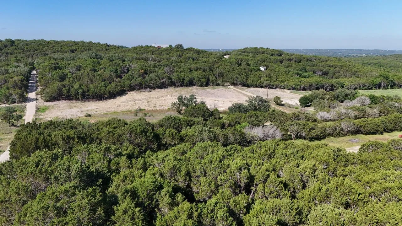 Expansive property featuring dense tree coverage, open clearings, and a defined track